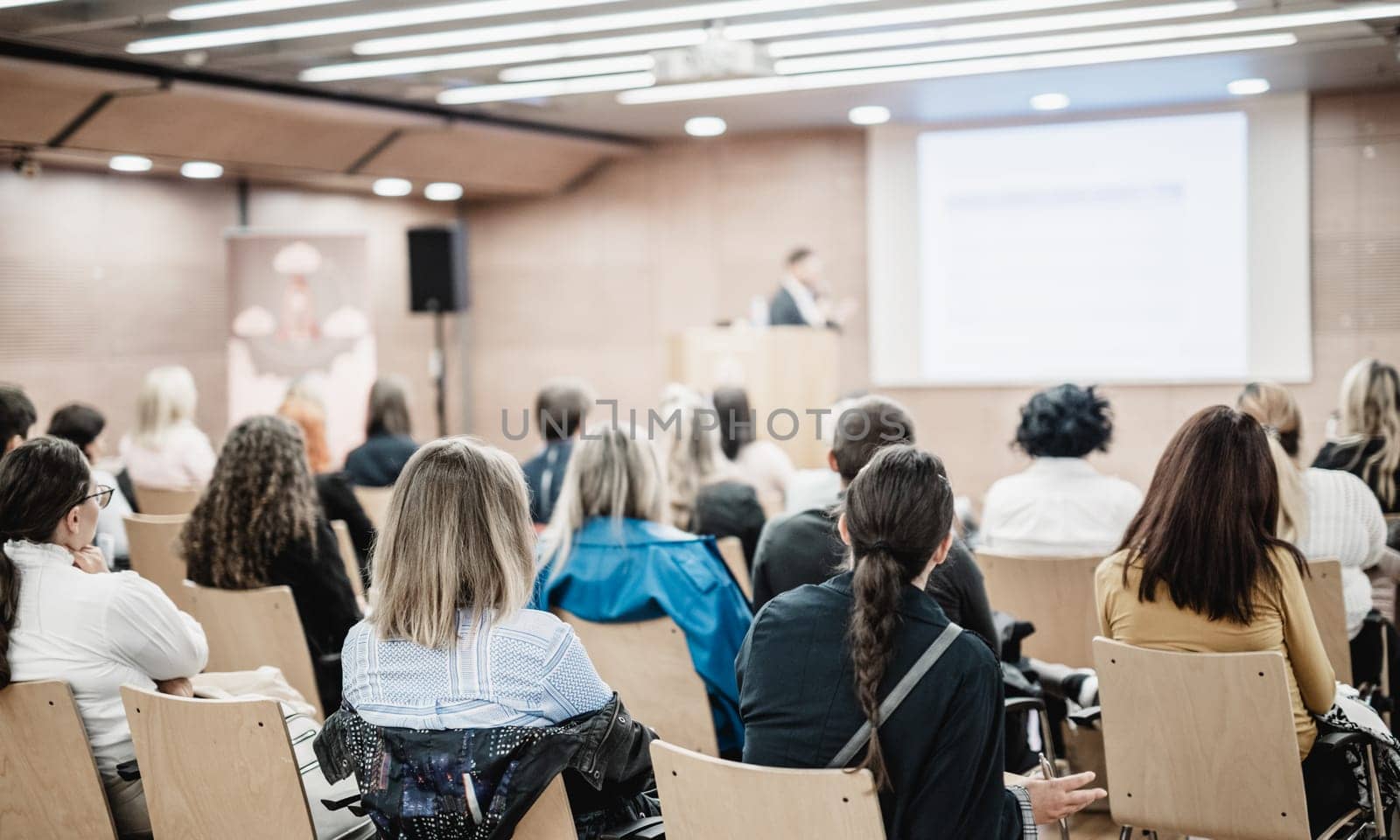 Speaker giving a talk in conference hall at business event. Rear view of unrecognizable people in audience at the conference hall. Business and entrepreneurship concept