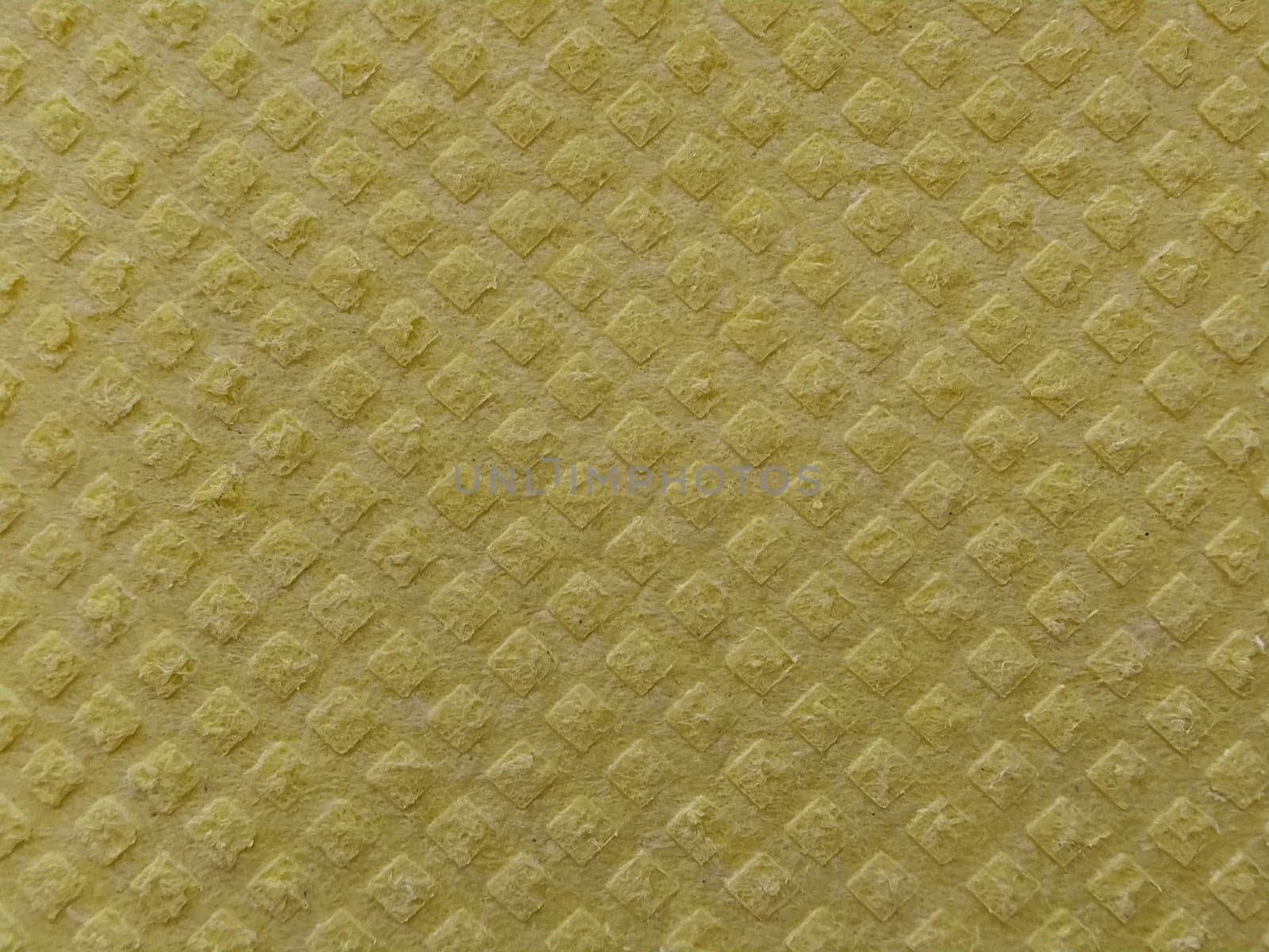 Close-up of fabric with embossed convex print. Bulging diamonds on yellow microfiber or dishwashing sponge. Background and free space for text.