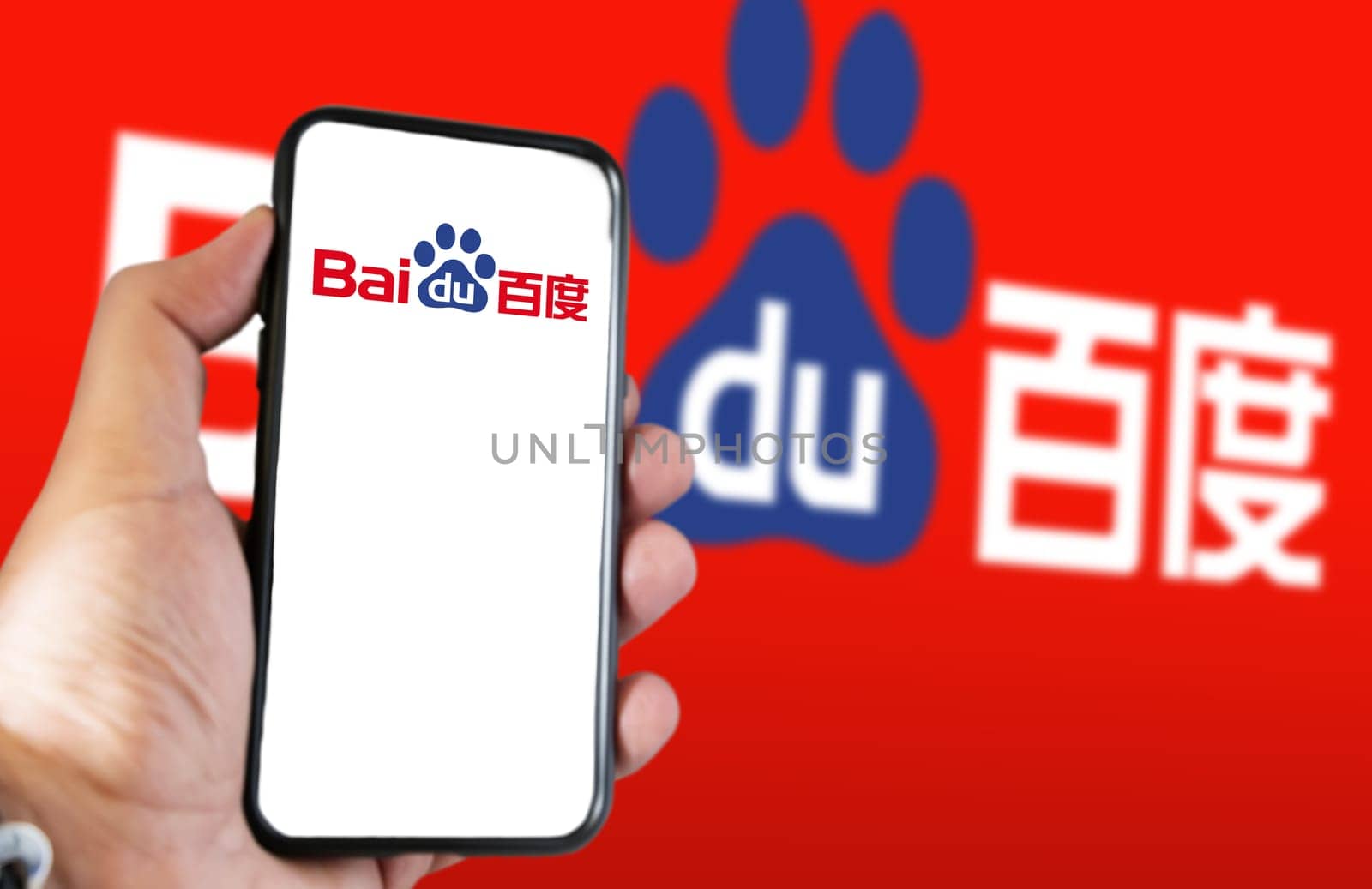 Beijing, CN, Feb 2023: A hand holding a phone with the Baidu website on the screen. Red background with blurred Baidu logo. Baidu is a Chinese multinational technology company