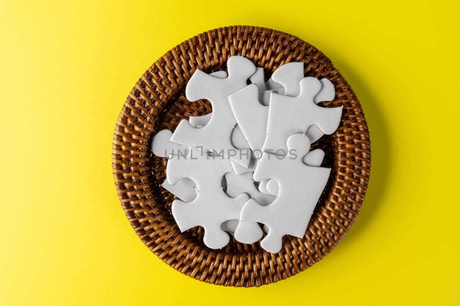 White jigsaw puzzle in container under yellow background