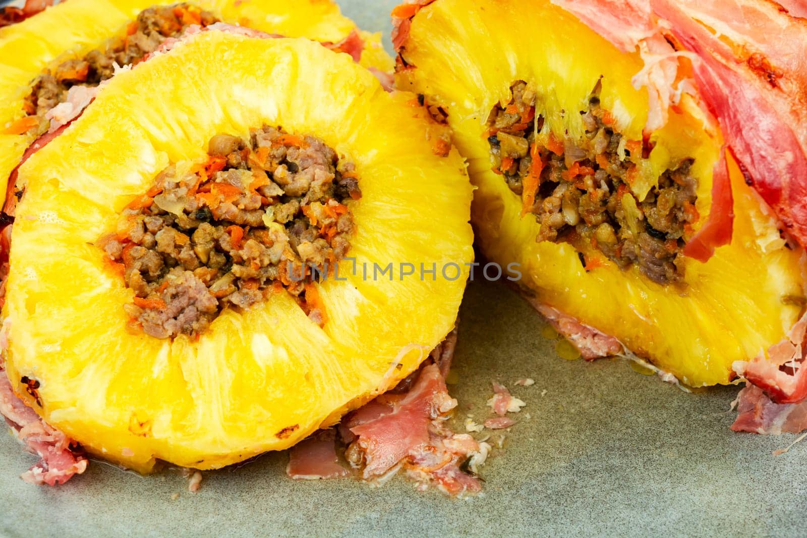 Tasty baked pineapple with spicy meat filling, wrapped bacon