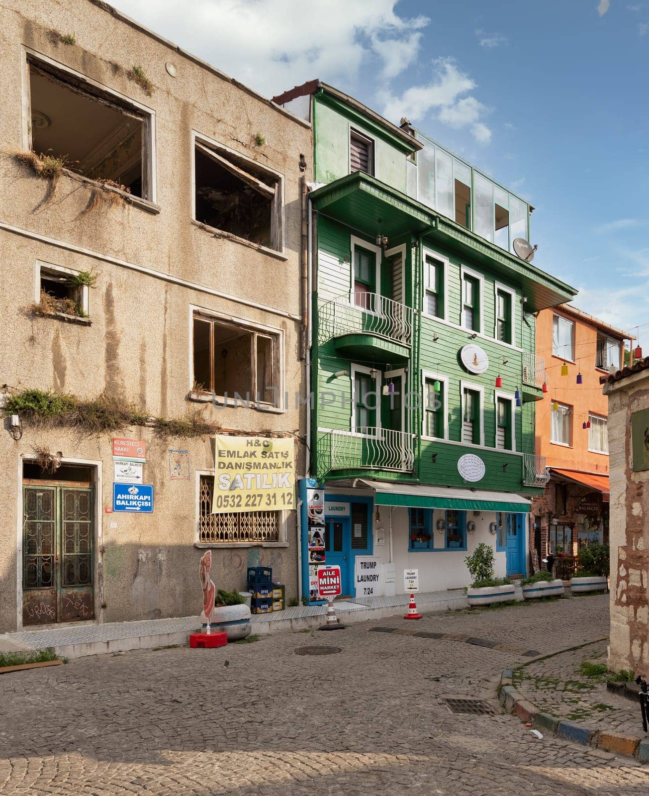 Istanbul, Turkey - August 30, 2022: Cobblestone alley, with beautiful old colorful traditional house, painted in green, suited in Kapiagasi Street, Fatih district, in a summer day