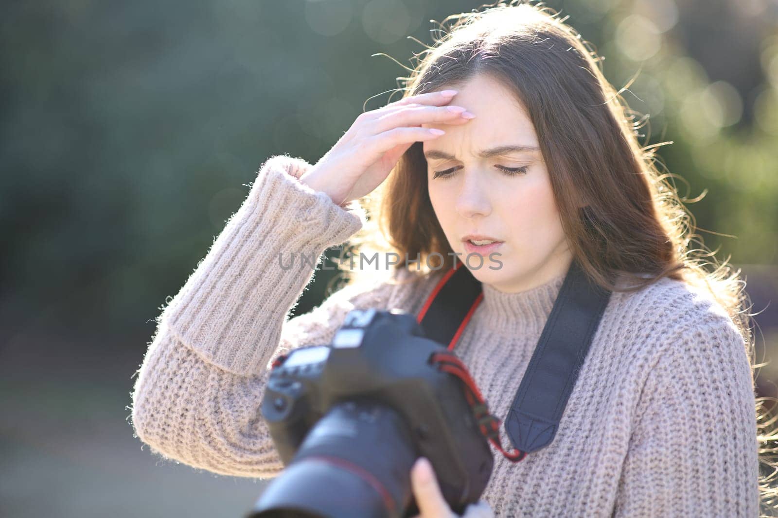 Worried photographer checking photos on dslr professional camera in winter