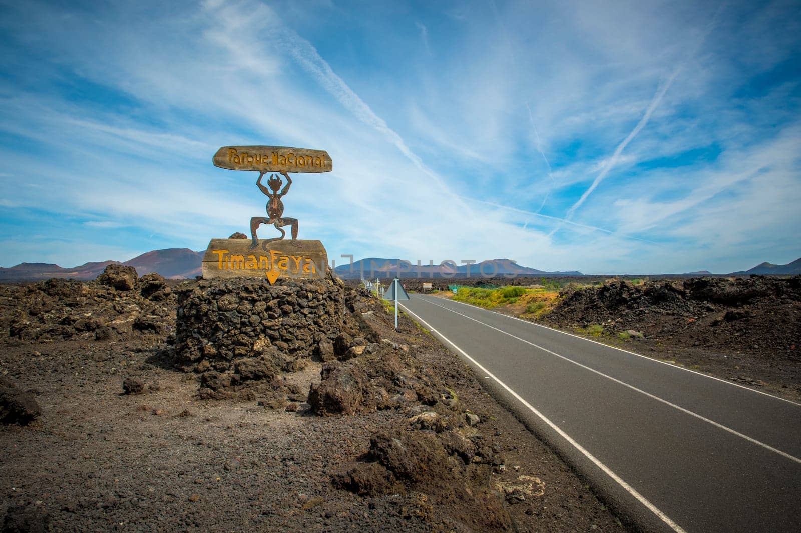 Timanfaya, Lanzarote, Spain, March 2023: View on the entrance sign and road of Timanfaya National Park on Lanzarote, Canary Islands. The El Diablo symbol was designed by Cesar Manrique.