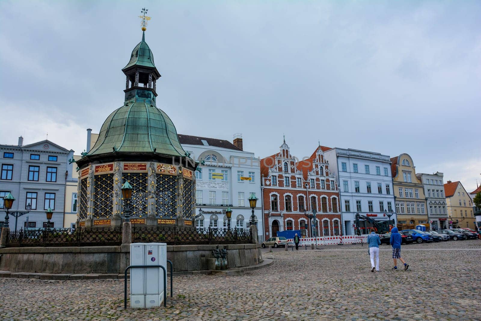 Wismar, Germany, September 10, 2022 - Street at the market square with the water art fountain in the middle of the historic Hanseatic city of Wismar, on the Baltic Sea coast of Mecklenburg-West Pomerania in Germany