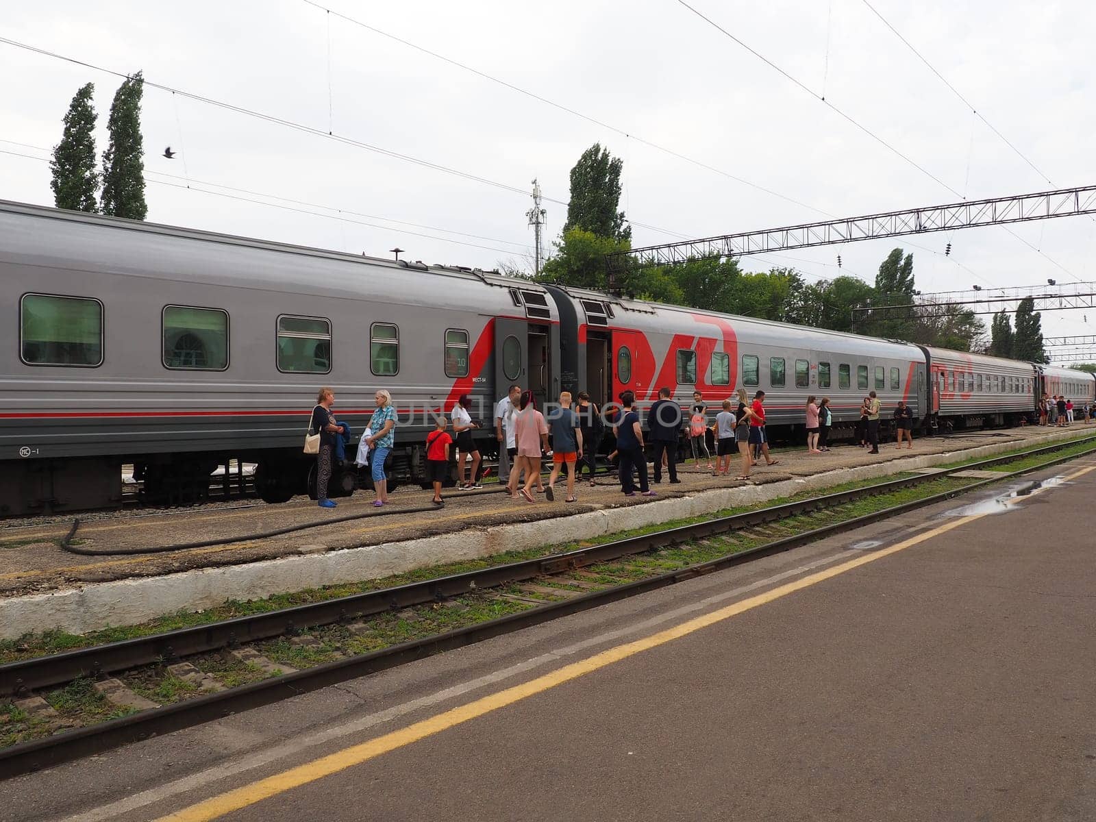 Usman, Lipetsk region, Russia, August 7, 2021. Station of the southeastern railway. The platform with people who got off the train. Russian Railways passenger train. Rails and sleepers. Stopover.