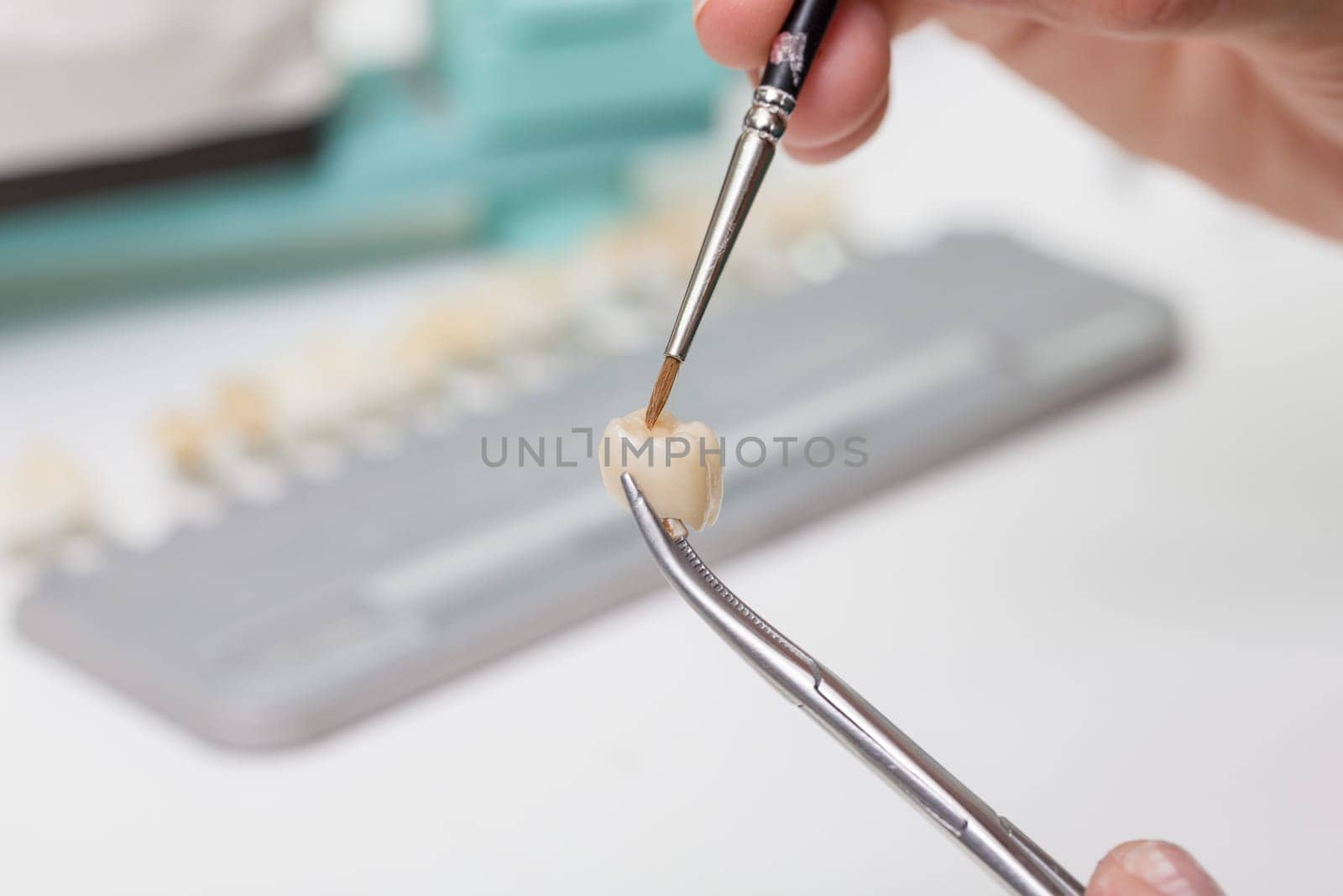 In a dental laboratory,a dental crown is colour-adjusted.