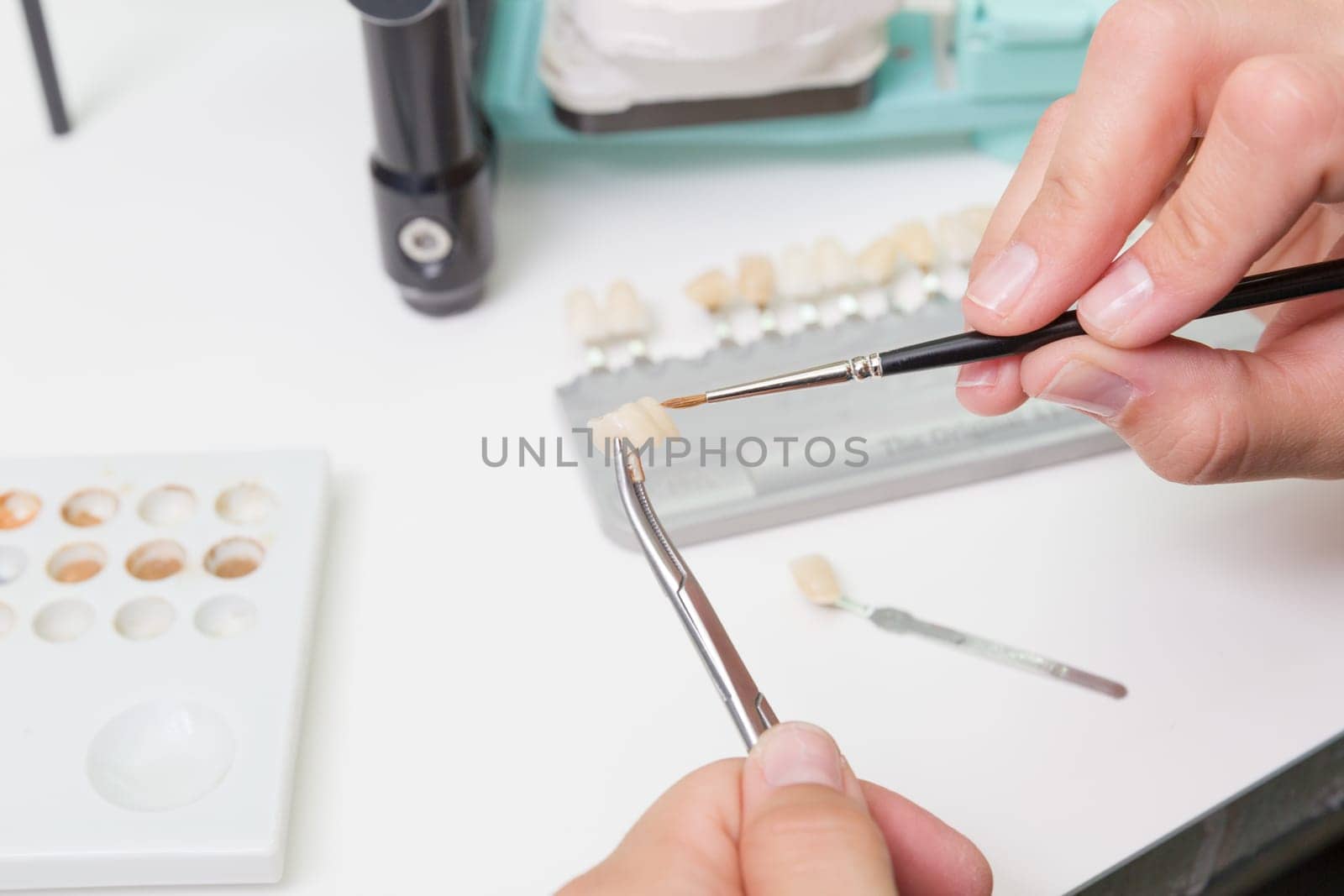 In a dental laboratory,a dental crown is colour-adjusted.