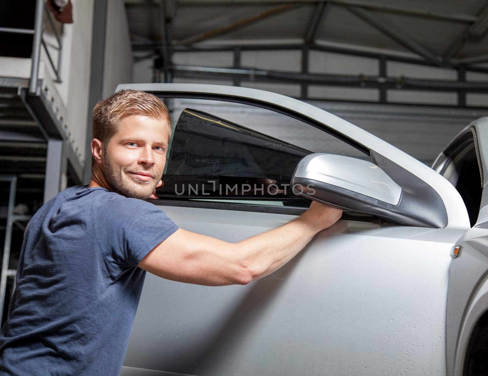 Applying tinting foil onto a car window in a workshop