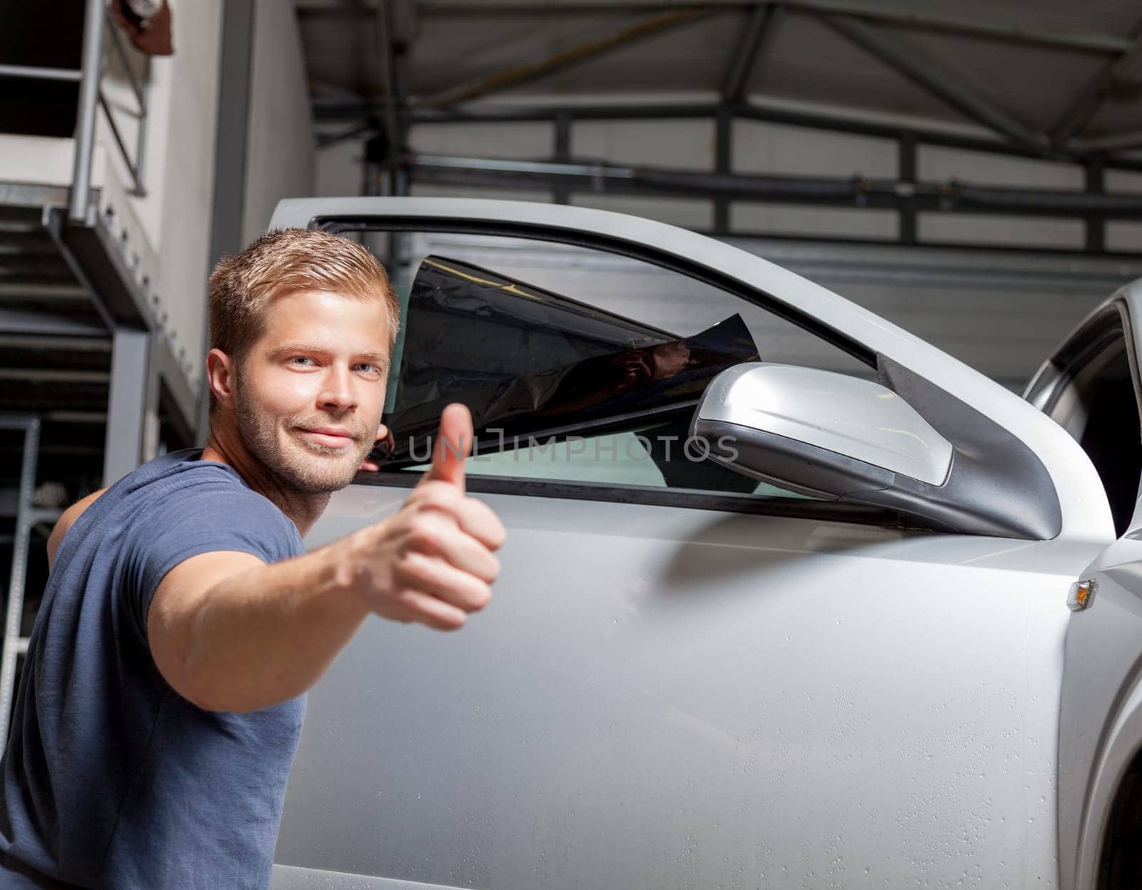 Applying tinting foil onto a car window in a workshop