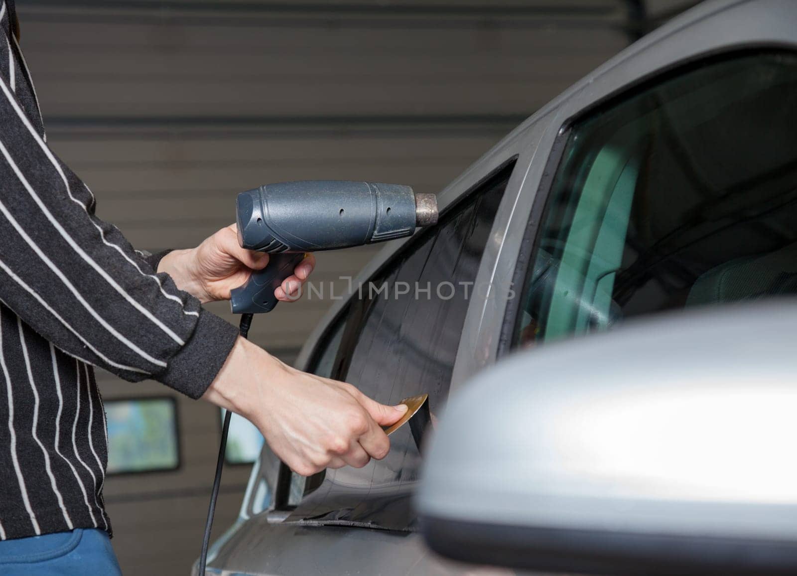 Applying tinting foil on a car window in a garage