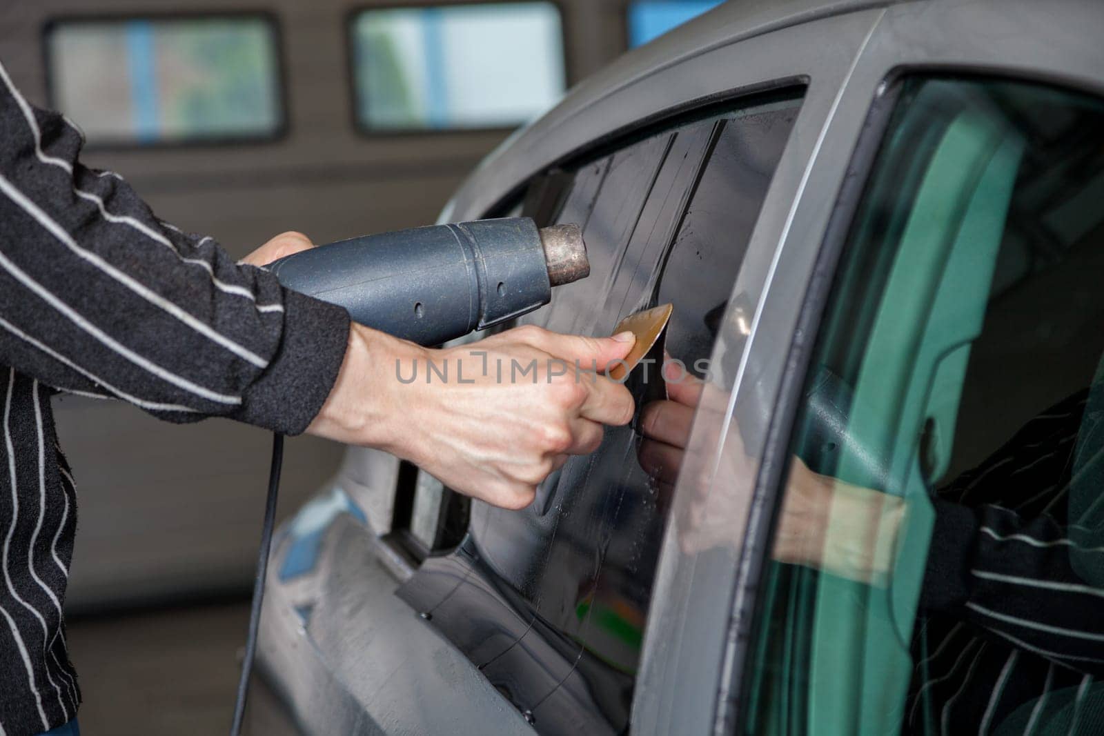 Applying tinting foil on a car window in a garage