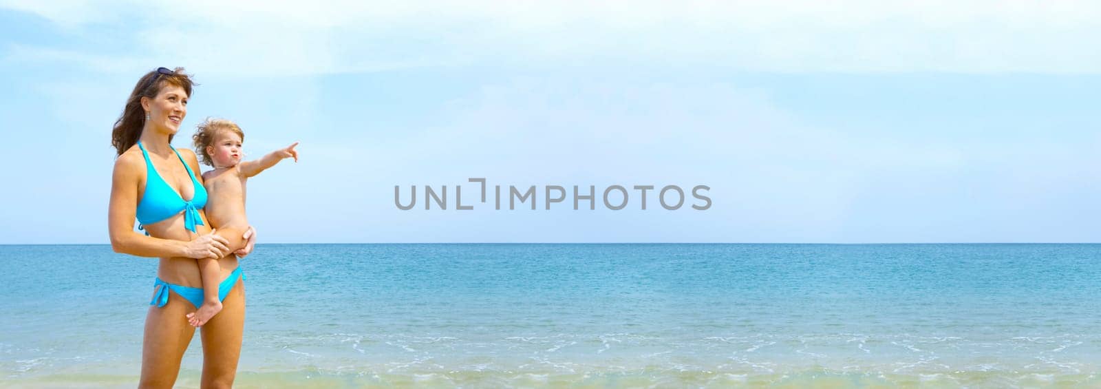 Portrait of young woman with her baby on beach.  Banner, lots of copy space.