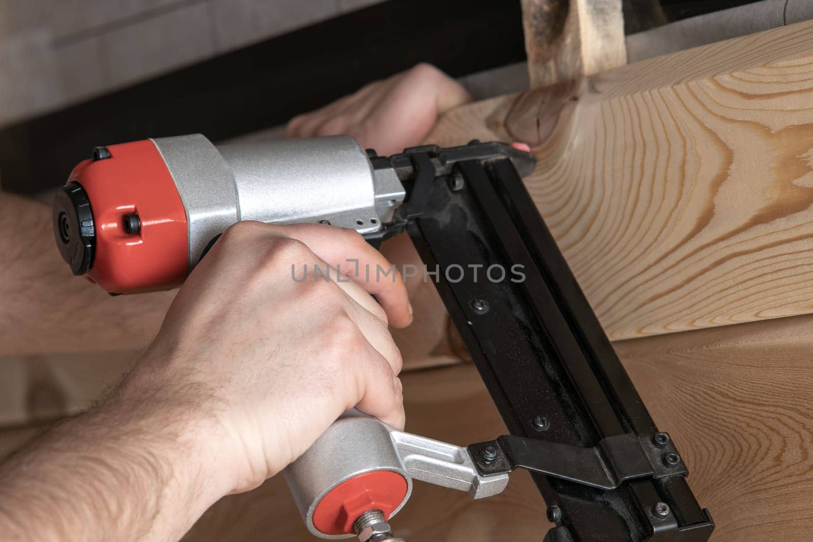 Cropped man hands using handy stapler, nail gun for wooden timber board, fastening with metal nails. Making layout on wooden plank. Woodworking and handicraft. Builder occupation, civil engineer