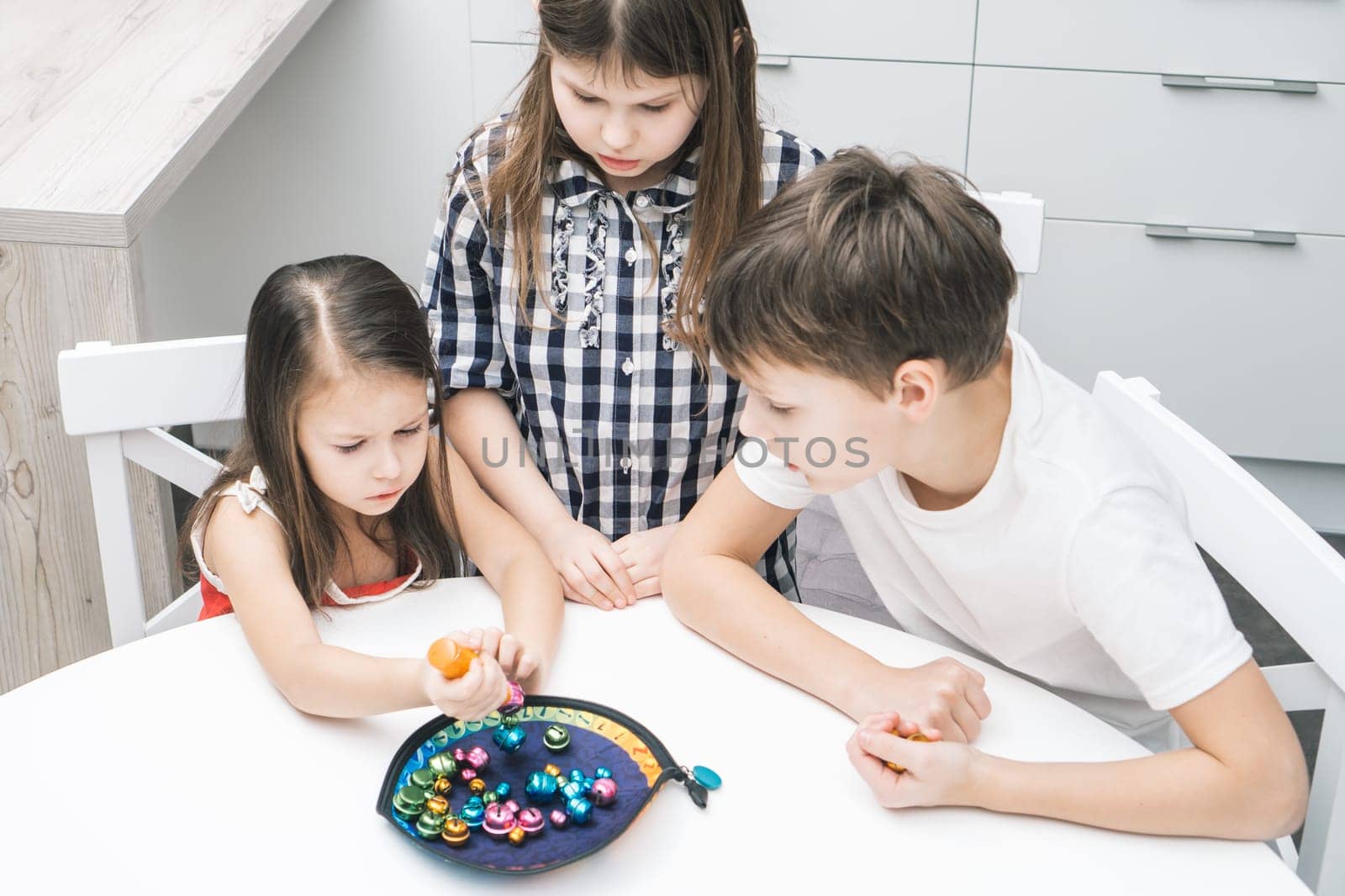Cloudy looking children of girls and boy looking at girl trying to catch fish bell from fish plate like fisherman. Fish rod games for motor and memory skills. Child development center, day care