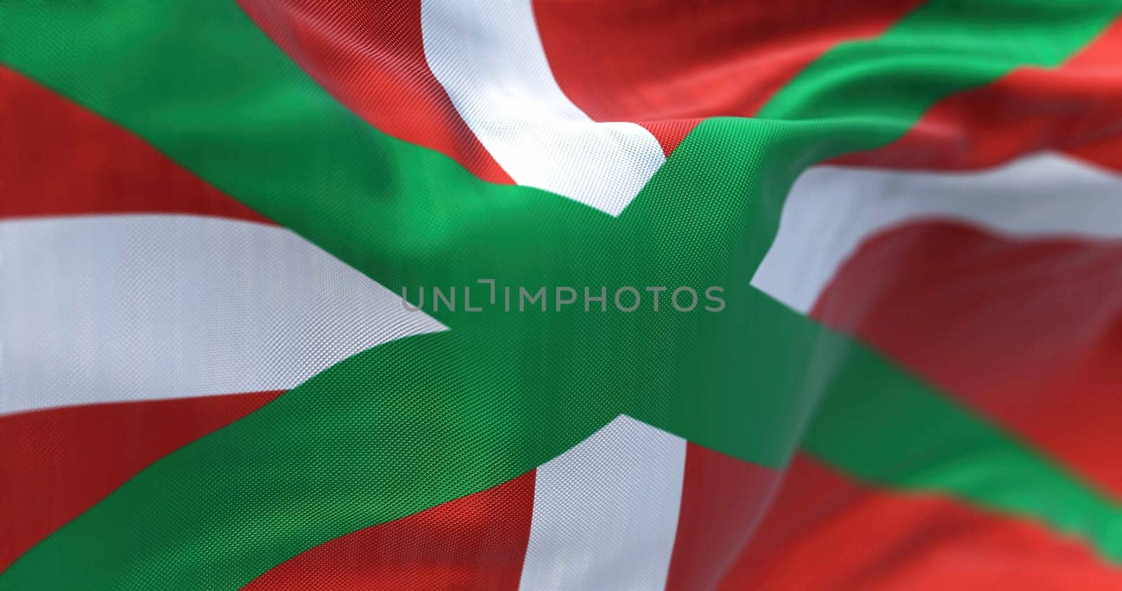 The Basque Country flag waving. Autonomous community in northern Spain. White cross over a green saltire on a red field. Selective focus. 3d illustration render. Close-up. Textured background
