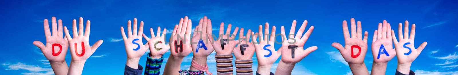 Children Hands Building Colorful German Word Du Schaffst Das Means You Can Do It. Blue Sky As Background.