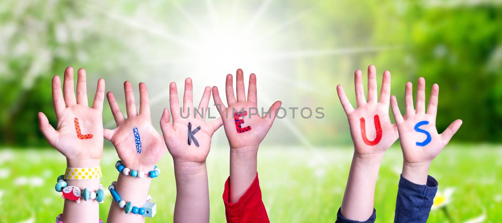 Children Hands Building Colorful English Word Like Us. Sunny Green Grass Meadow As Background.