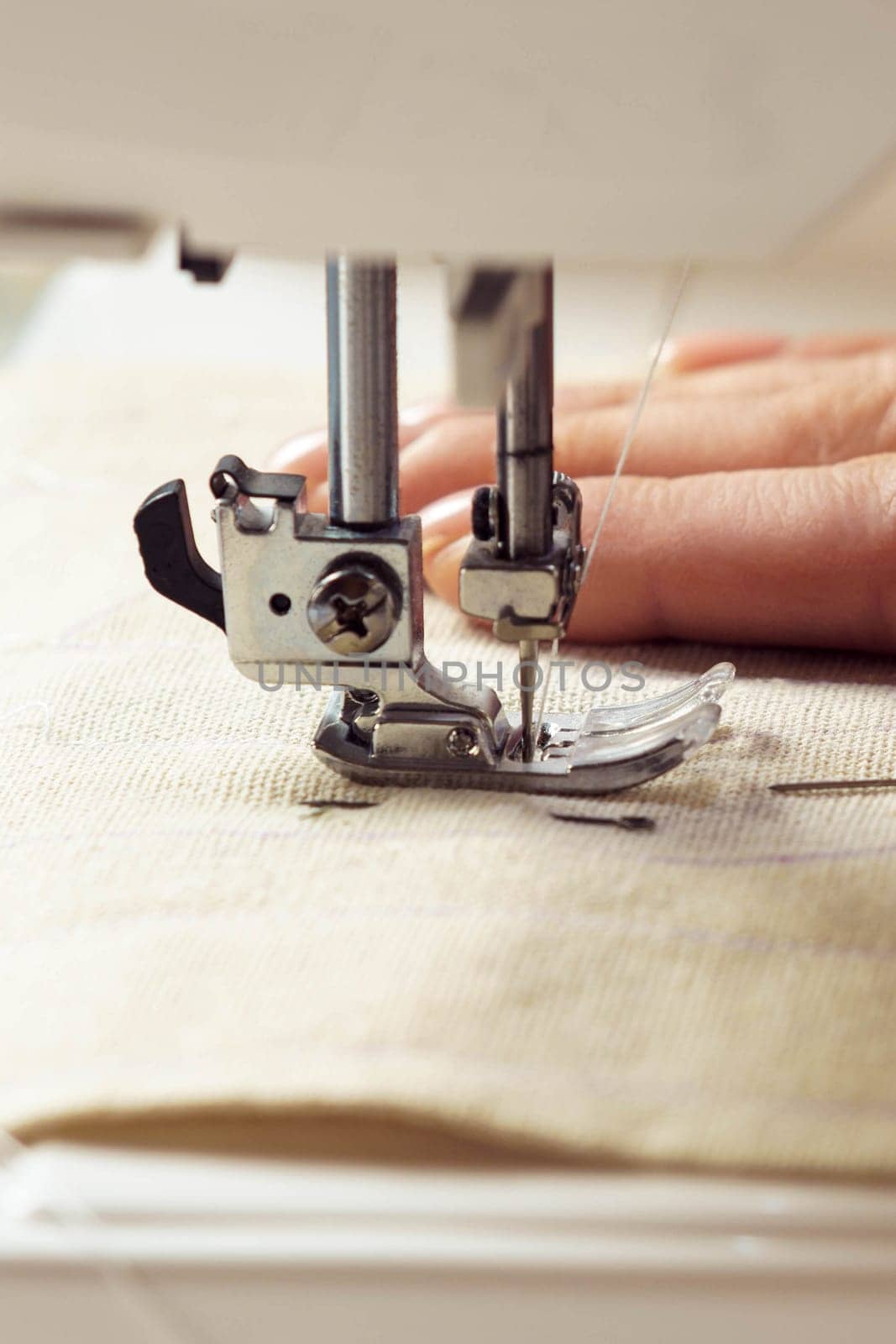 Vertical close up cropped woman hands using sewing machine for repair clothes with thread stitching. Tailor, seamstress handcrafting, sewing stuff. Handmade work, extremely close up of presser foot