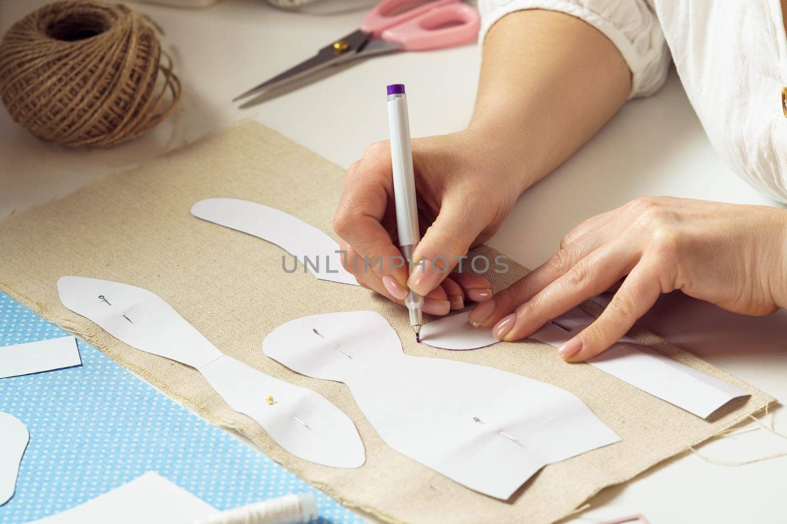 Sewing patterns for future toy or clothes work processing. Cropped designer, seamstress pin and make paper sewing patterns, painting contour on textile sheet. Entrepreneur work, hobby and business