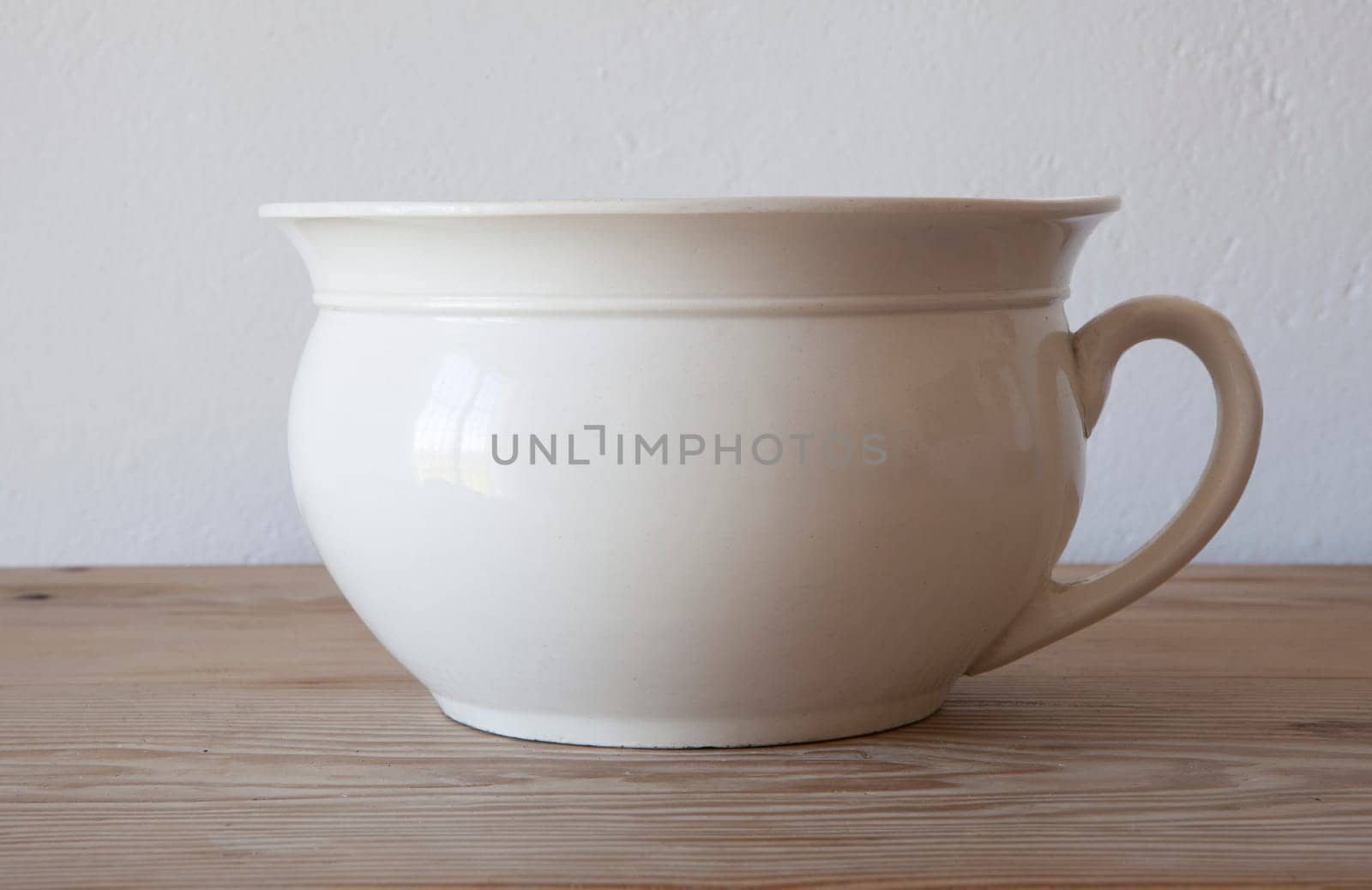 White porcelain camber pot over wooden surface. Selective focus