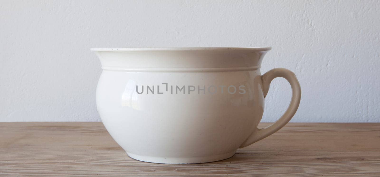 White porcelain camber pot over wooden surface. Selective focus