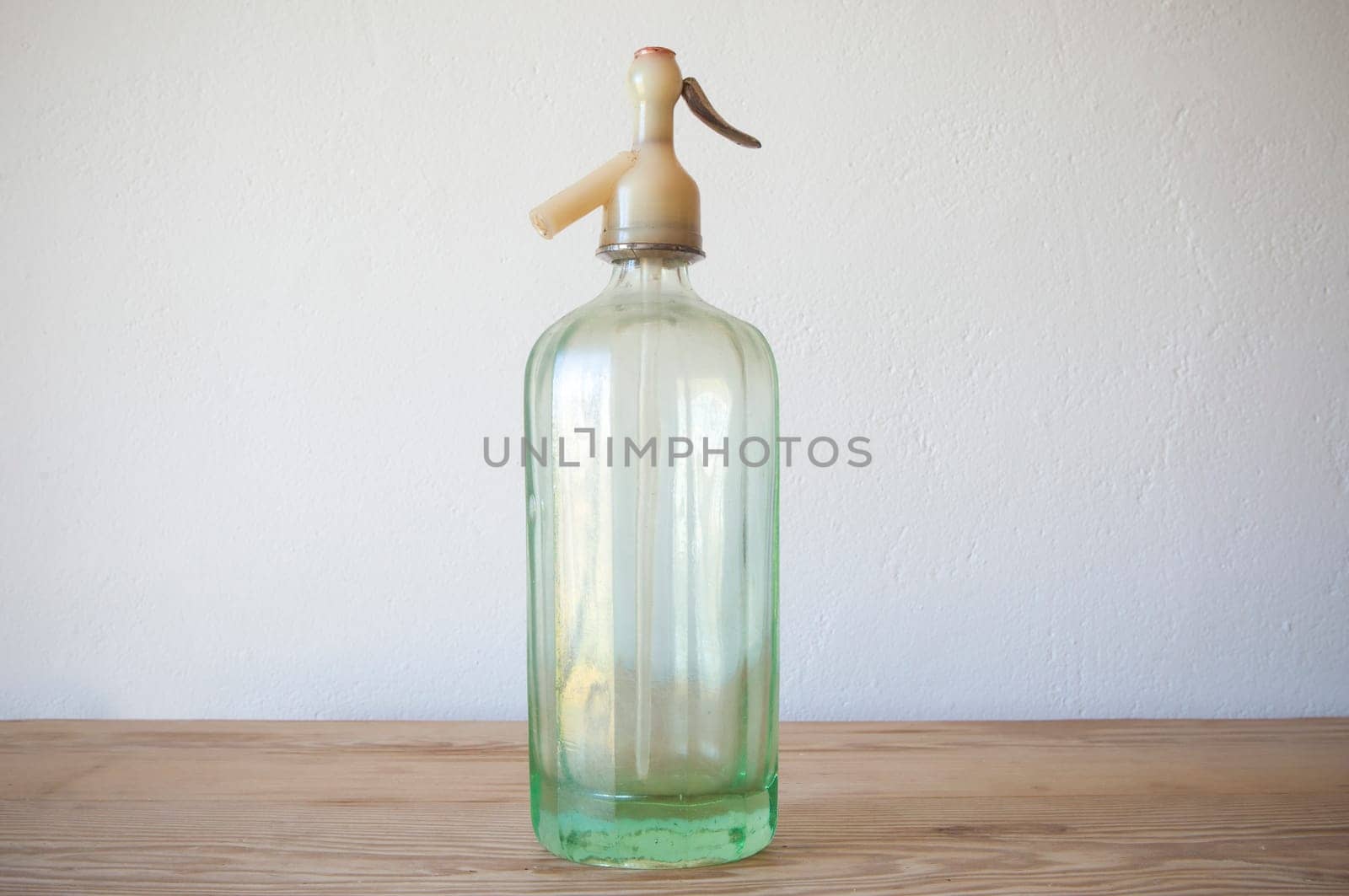 Old glass soda siphon. Wooden surface