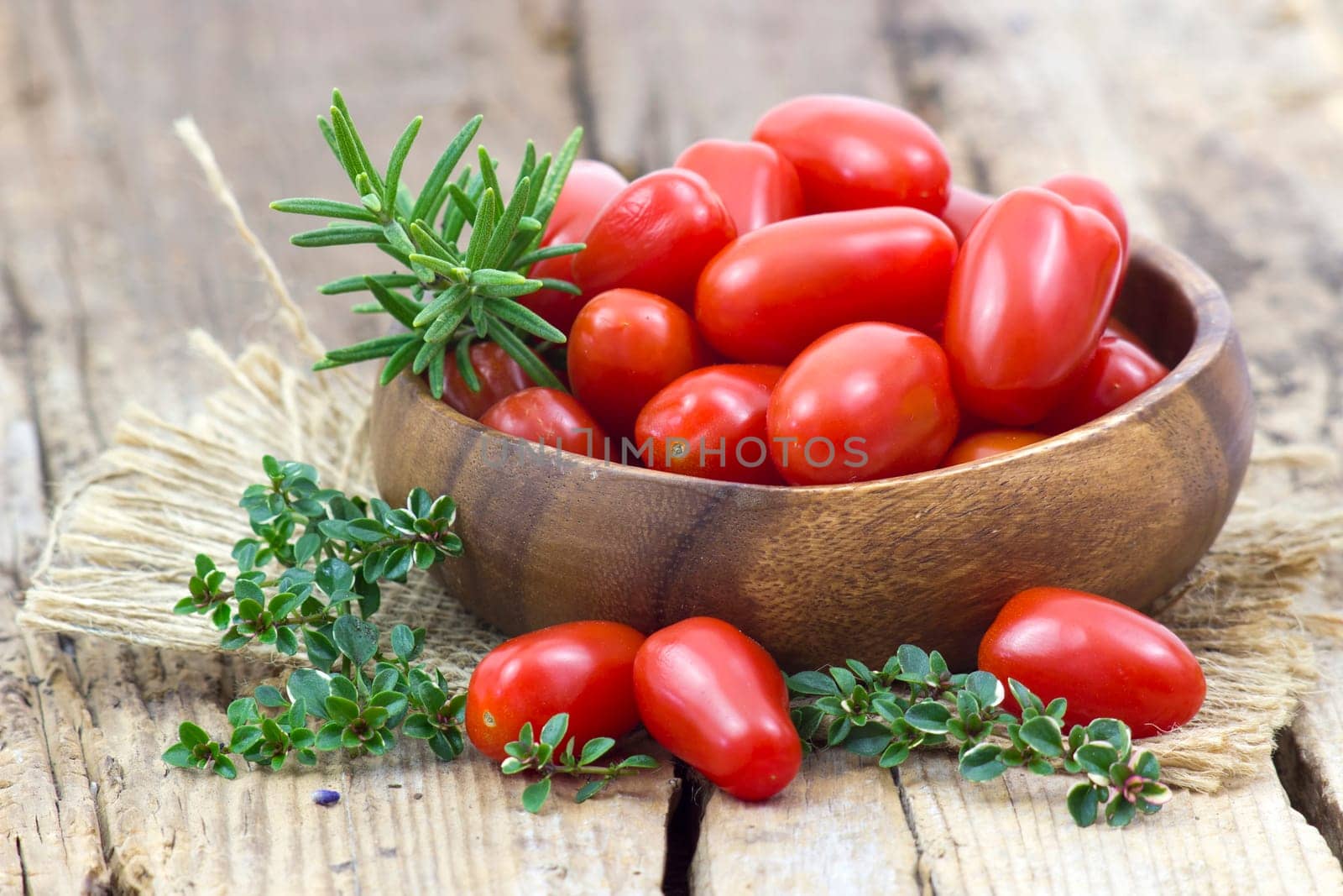 mini roma tomatoes and herbs on wooden background