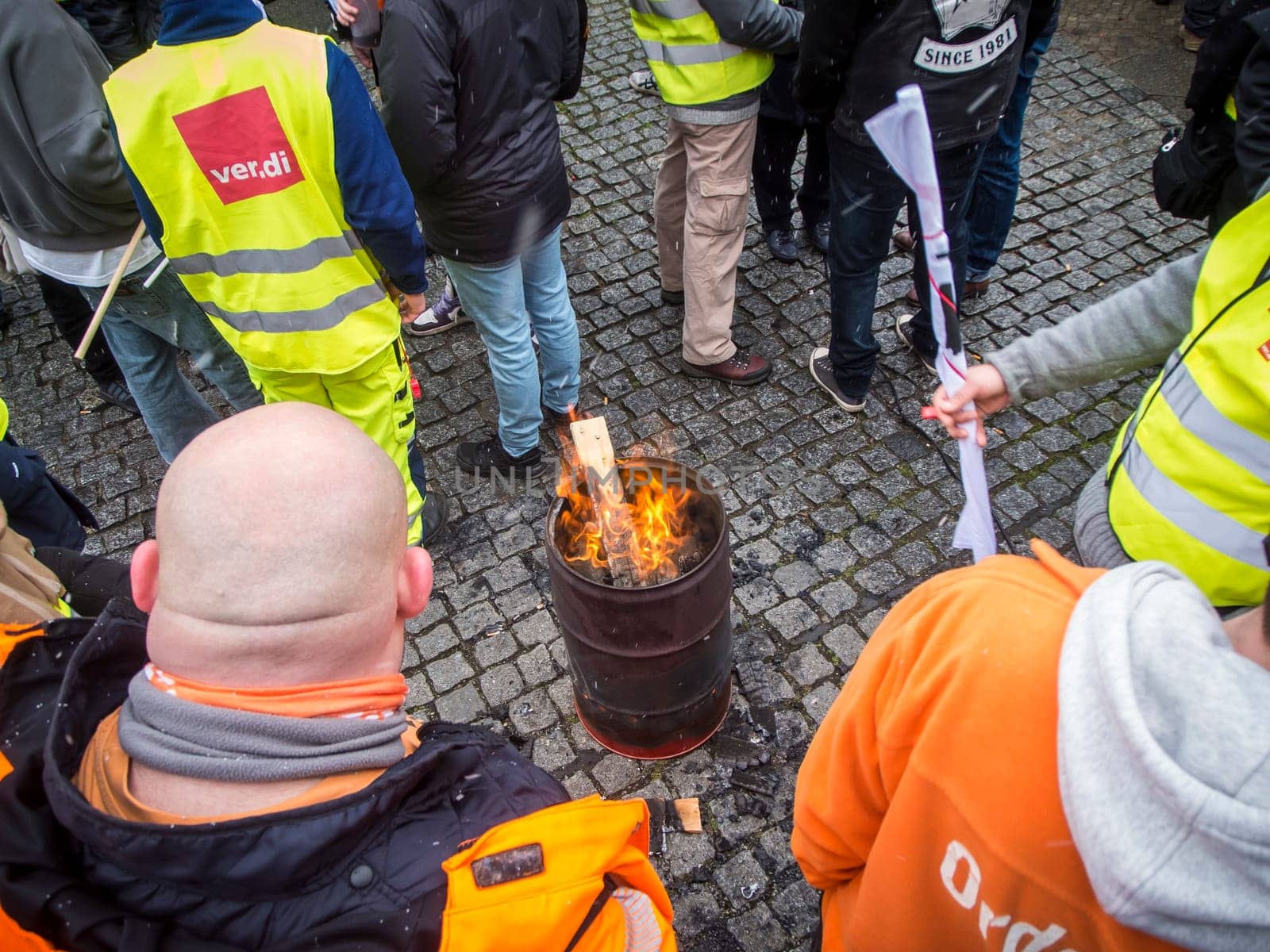 Berlin, Germany - March 06, 2023: Warning strike in front of the gates of the Berliner city cleaning company with orange smoke and waving flags of the union Verdi.