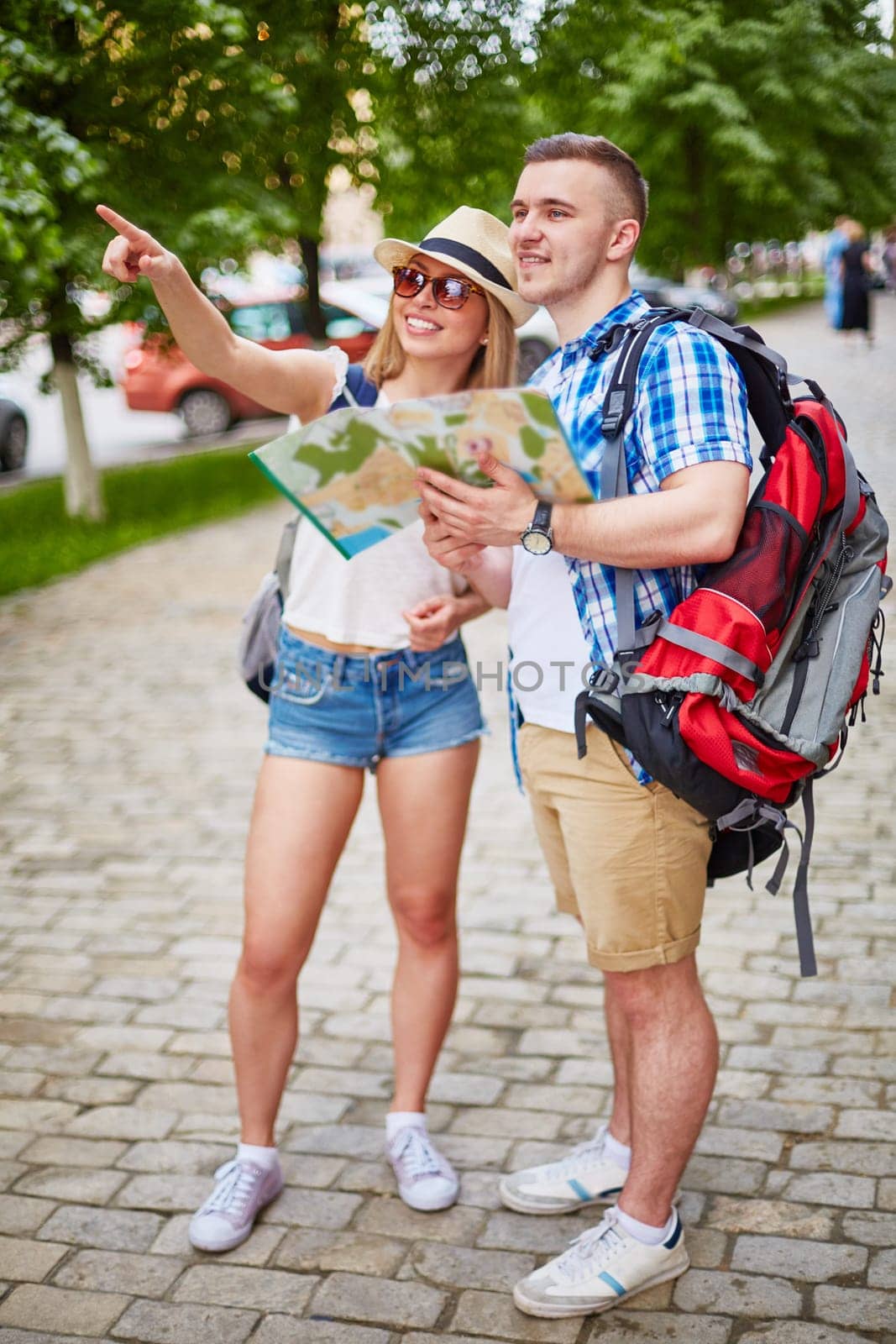 Happy tourists with rucksacks and guide choosing place to visit