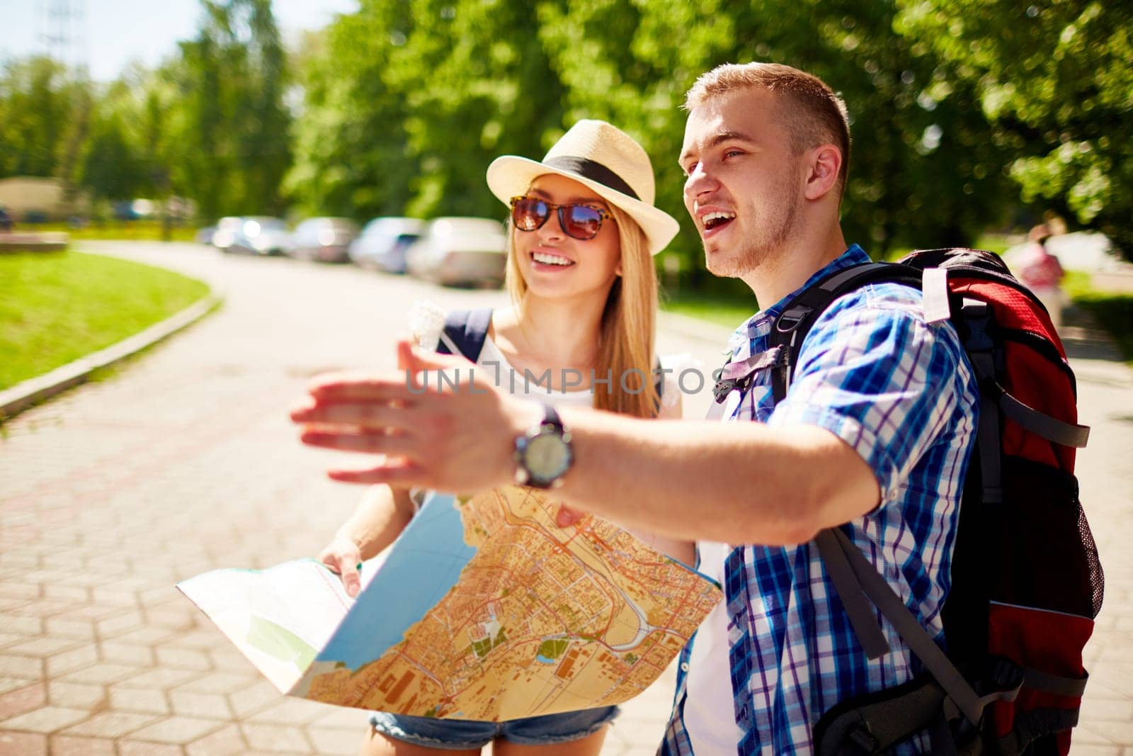 Happy travelers with rucksacks and guide spending vacation in foreign city
