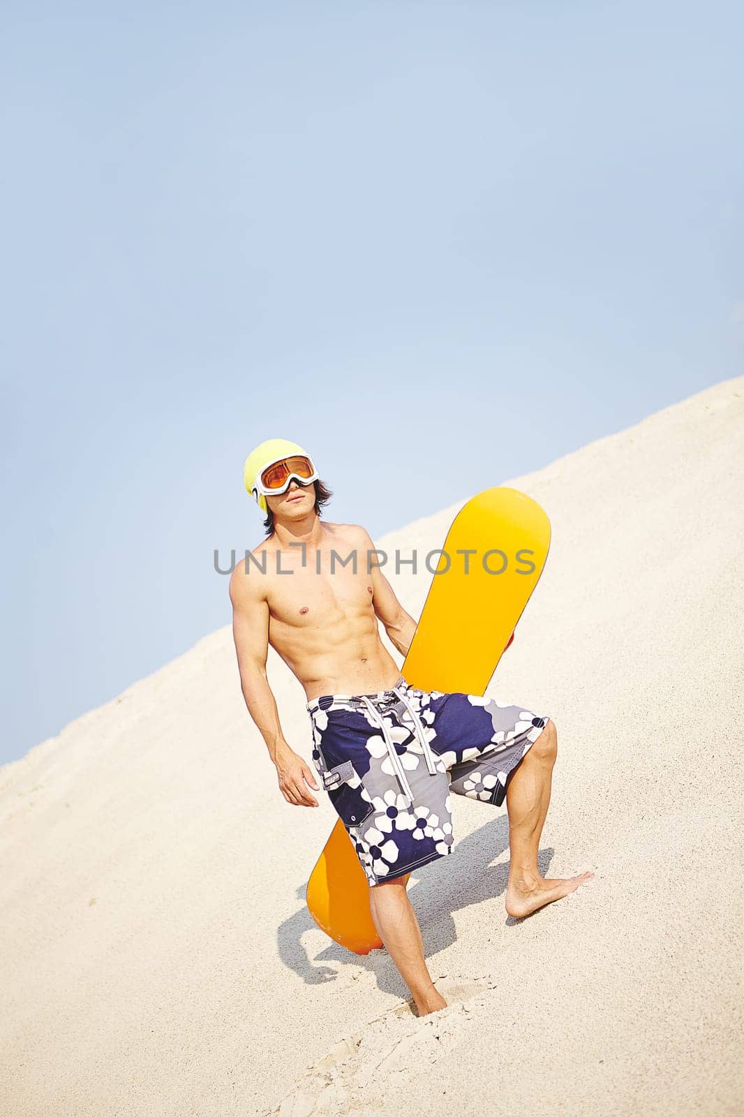 Young man with sandboard standing on beach