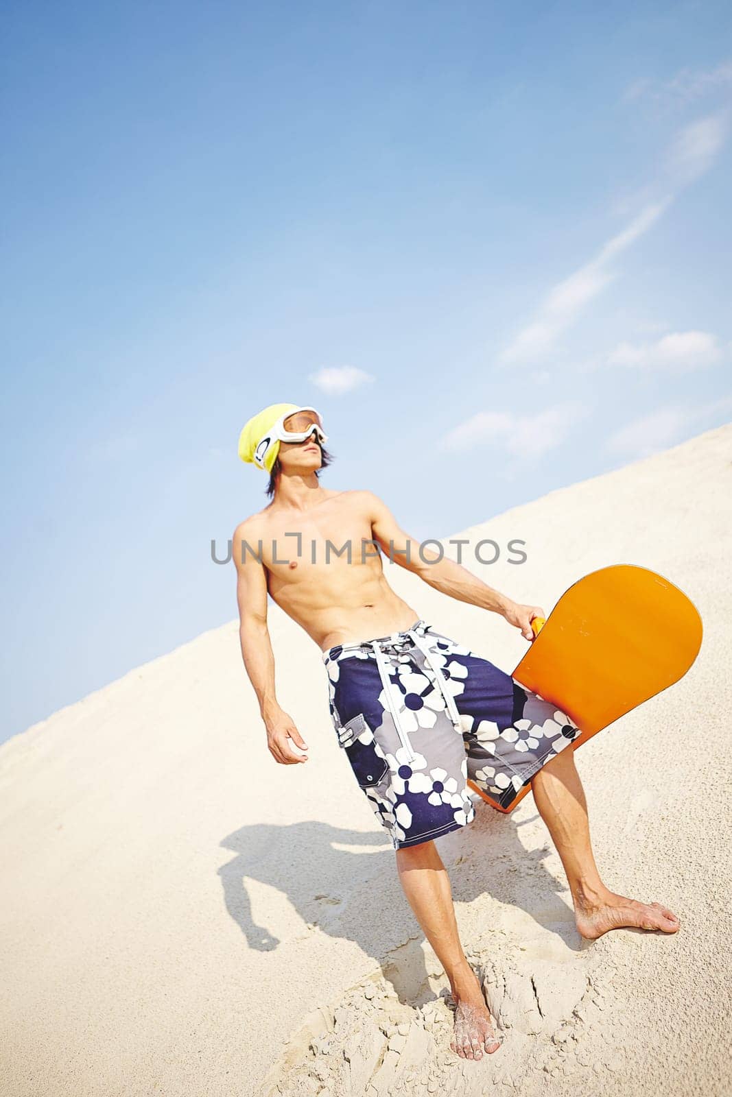 Fit young man with sandboard spending leisure on beach