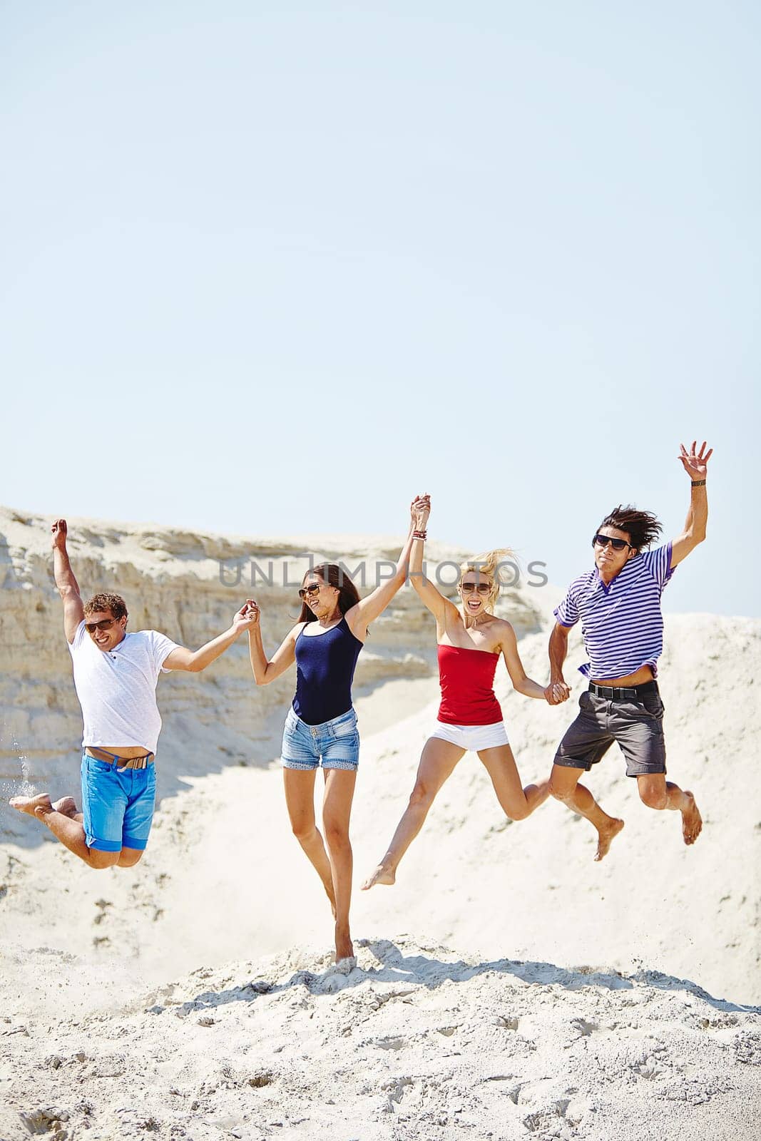 Happy friends jumping over sandy beach