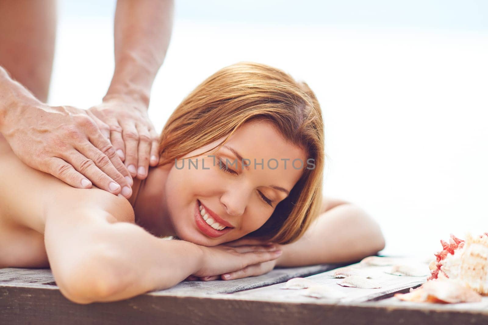 Young woman enjoying massage at summer resort