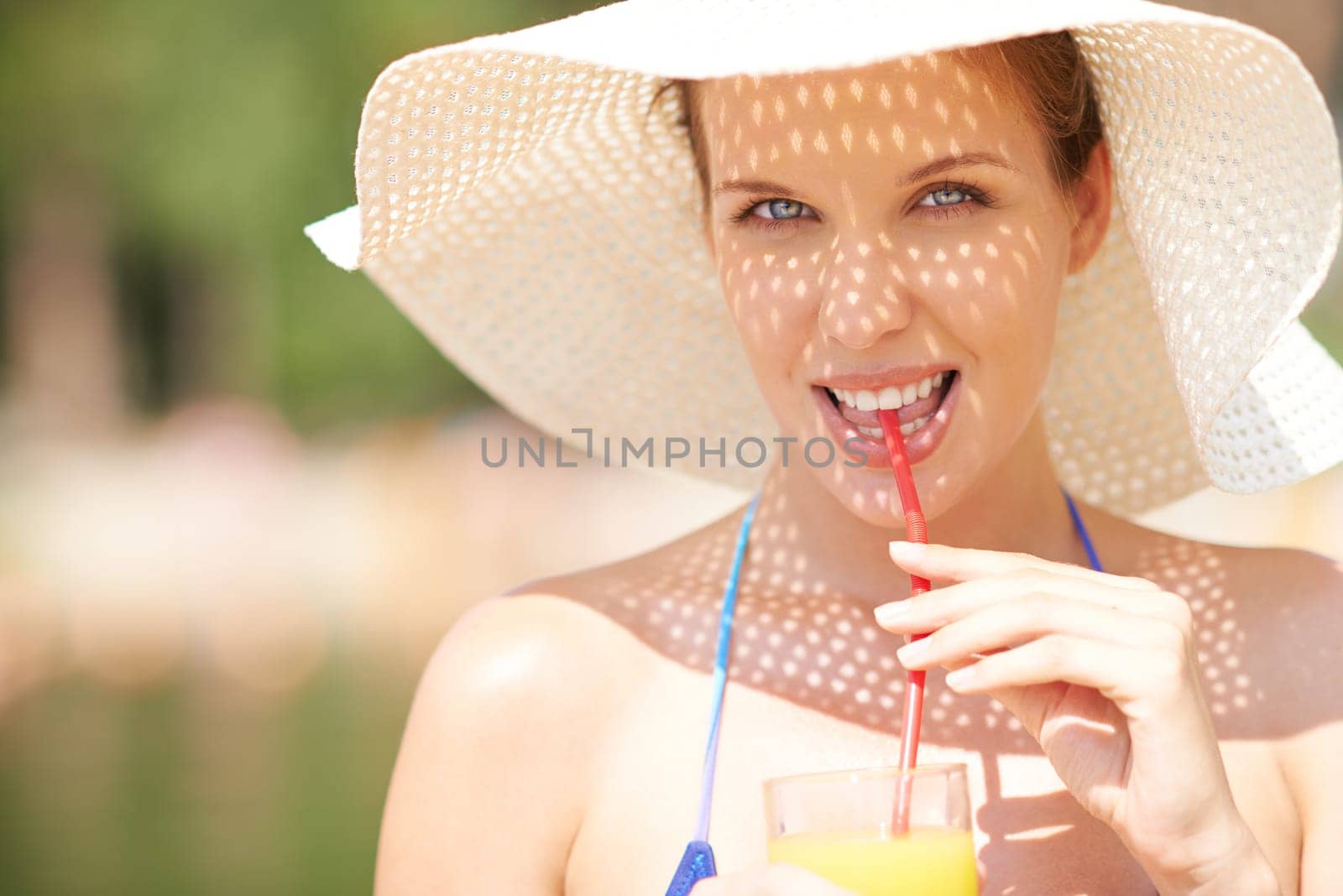 Happy female in sunhat drinking orange juice