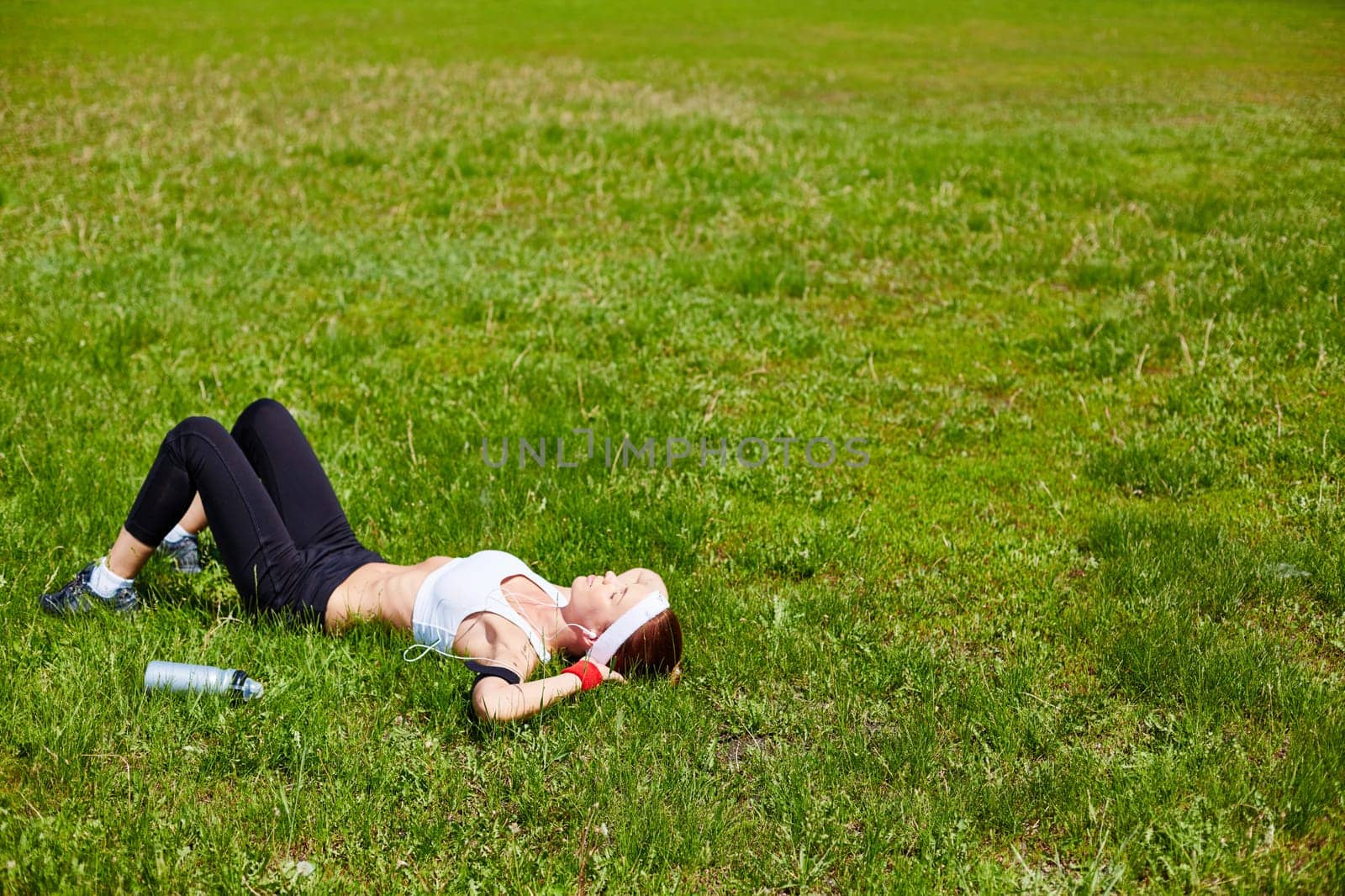 Young woman in activewear relaxing on green lawn