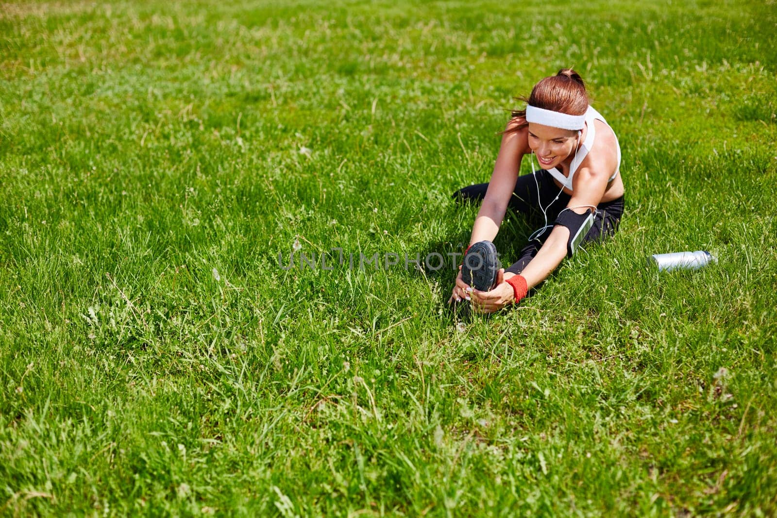 Young sporty woman exercising on green lawn