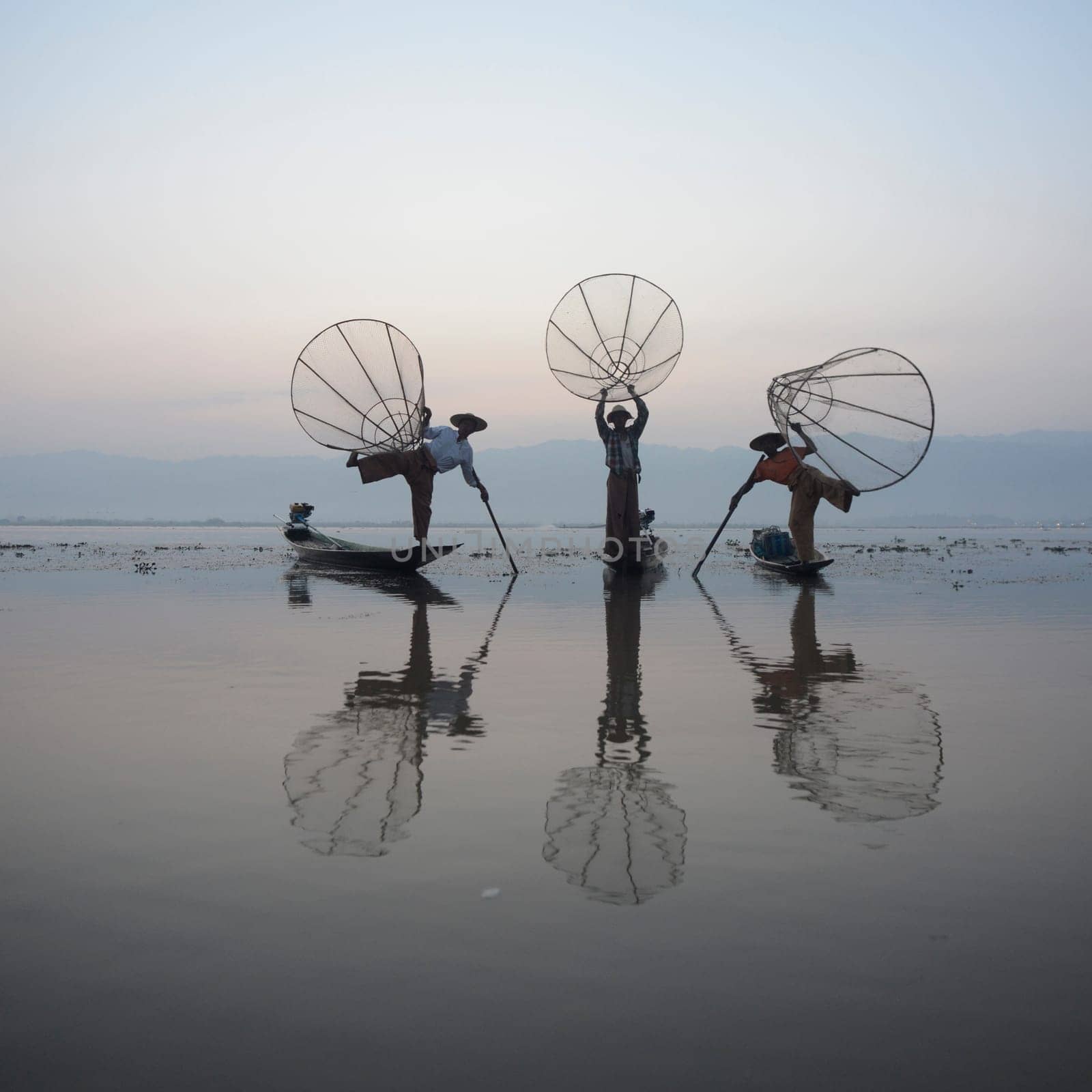 Fishermen at sunrise in the Landscape on the Inle Lake in the Shan State in the east of Myanmar in Southeastasia.