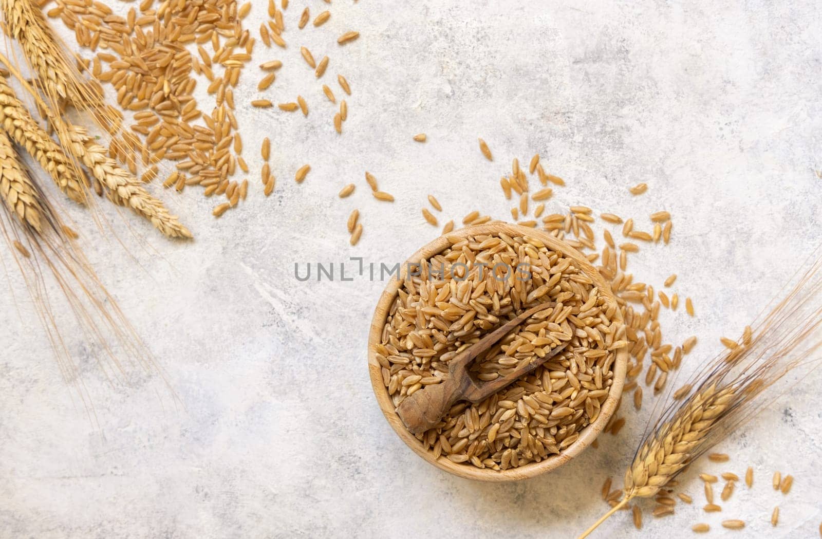 Bowl of raw dry rye grain with a wooden spoon on white table top view. Healthy alternative low gluten seeds. Protein source for vegan and vegetarian diet.