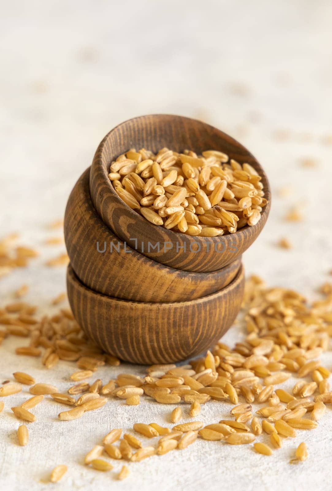 Wooden bowls of raw dry rye grain on white table close up. Healthy alternative low gluten seeds. Protein source for vegan and vegetarian diet.