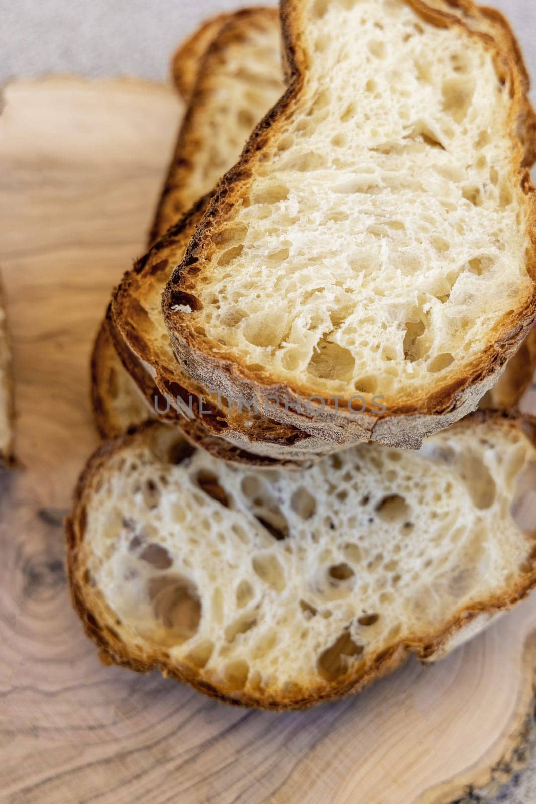 Fresh bread slices on wooden table. Concept of traditional leavened bread baking methods. Healthy food, homemade baked goods.