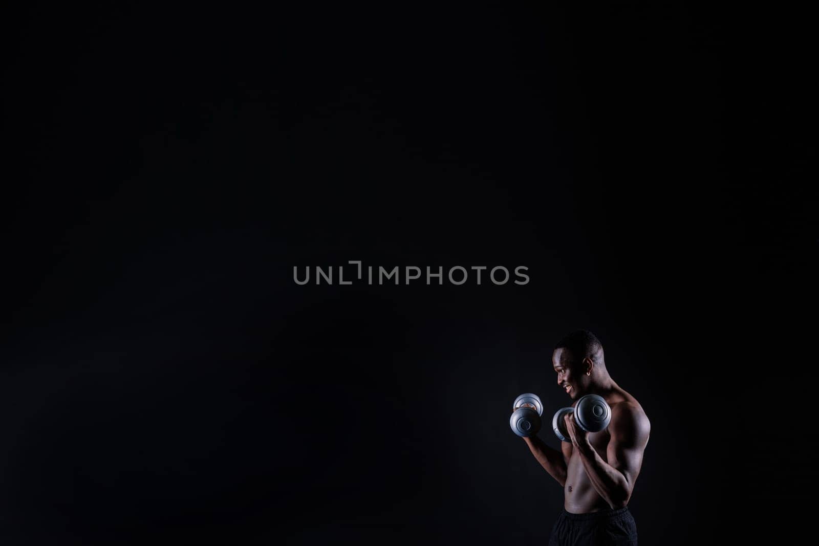 One young african muscular build man standing topless silhouette isolated on a black background