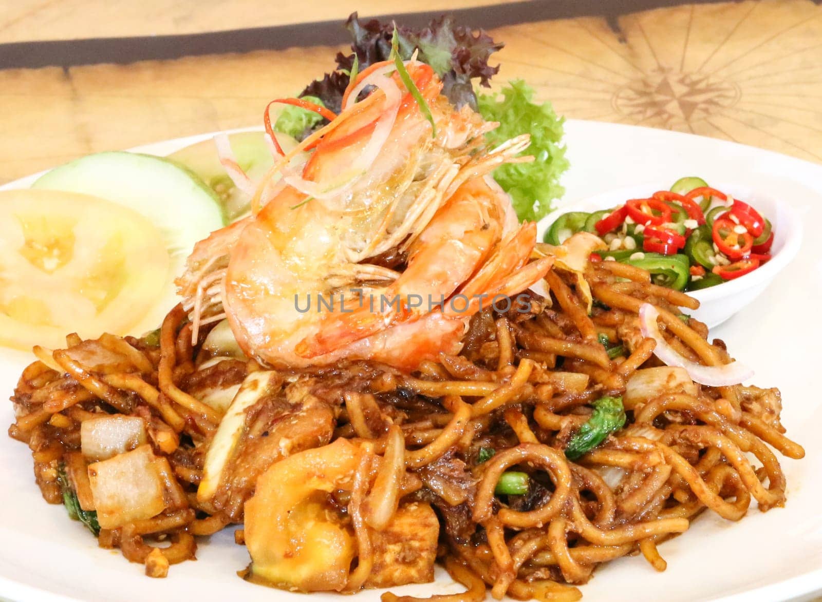 Fried noodles, mee goreng or mi goreng served with prawns. Popular dish in Southeast Asia.