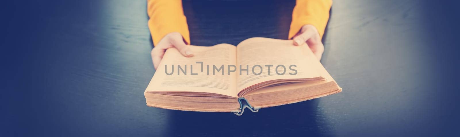 Woman sitting indoors and reading a vintage book. Concept of wisdom and knowledges.