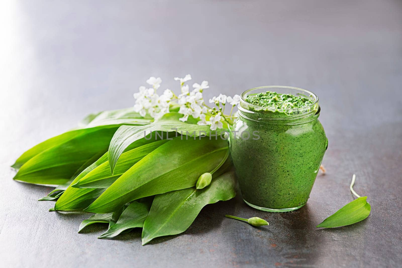 Fresh ramson or wild garlic pesto in glass jar close up. Healthy spring food concept