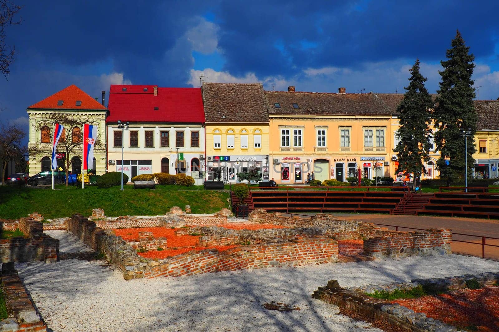 Sremska Mitrovica, Serbia, March 16, 2023 Zitni trg historical square. Ancient multi-colored buildings and excavations of Roman times. Cultural heritage. Dramatic sky. Excavations of Roman chambers