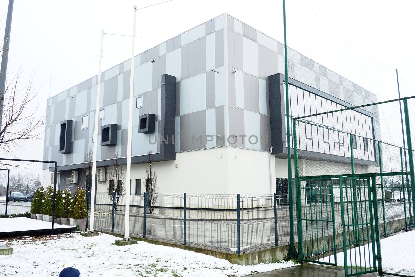Sremska Mitrovica, Serbia, January 27, 2023. City swimming pool building. Pinky Swimming Pool, next to the Pinky Sports Centre. Modern sports building, gray and white ventilated facade. Snow in winter