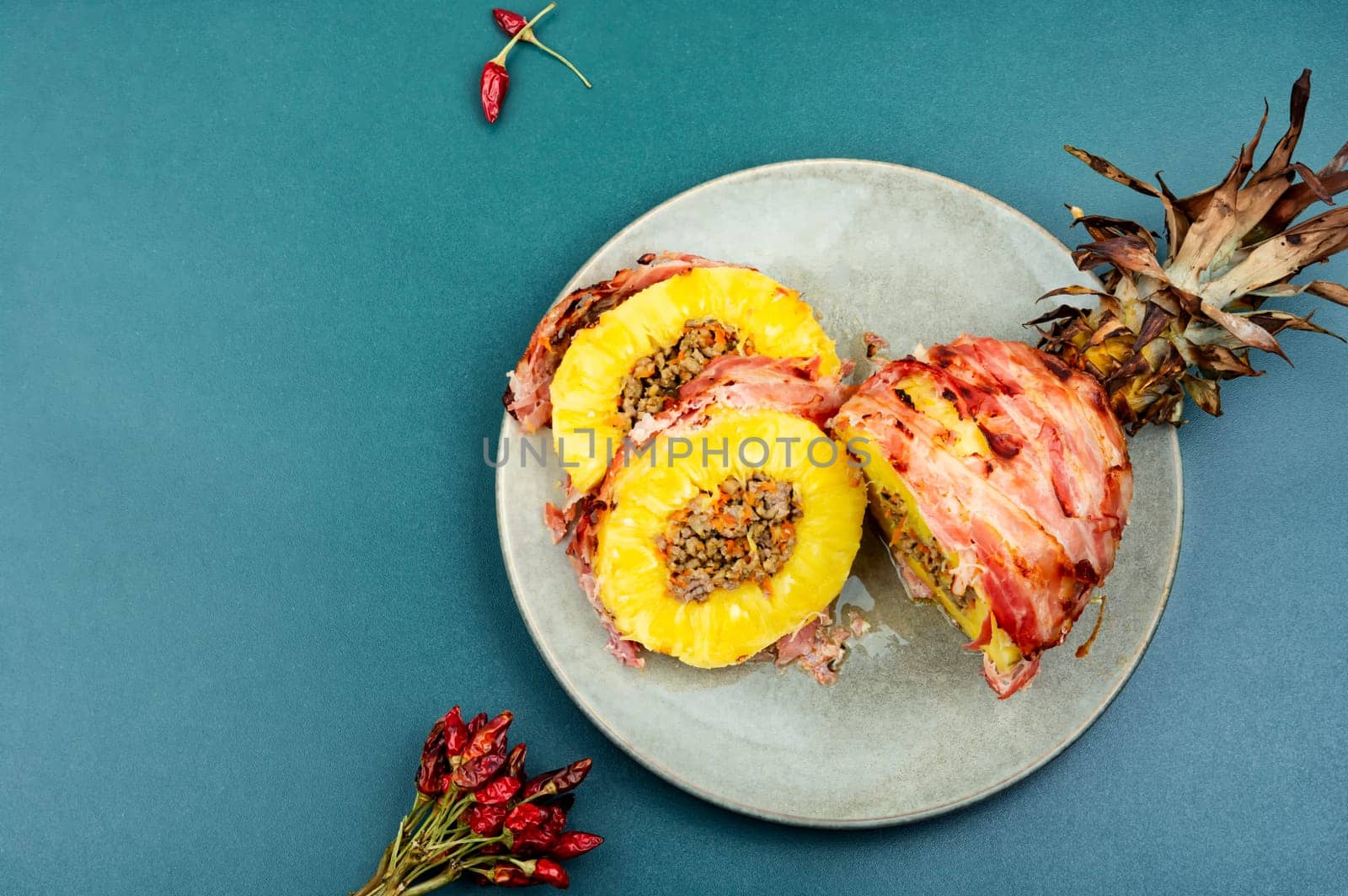 Delicious baked pineapple with spicy meat filling, wrapped bacon
