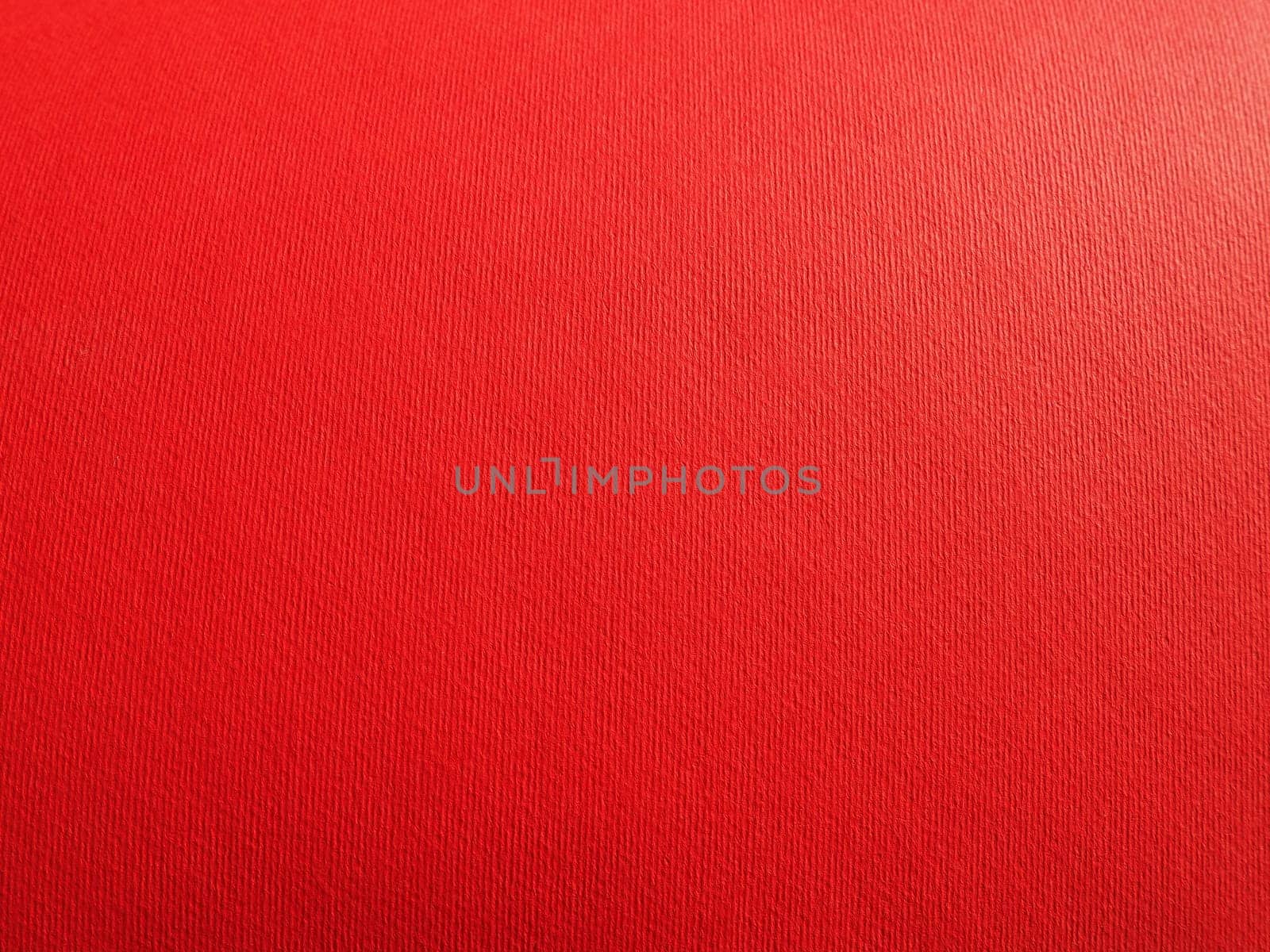 Abstract red background with texture. Close-up of paper surface with light and color gradient. Side lighting. Bright crimson backdrop.